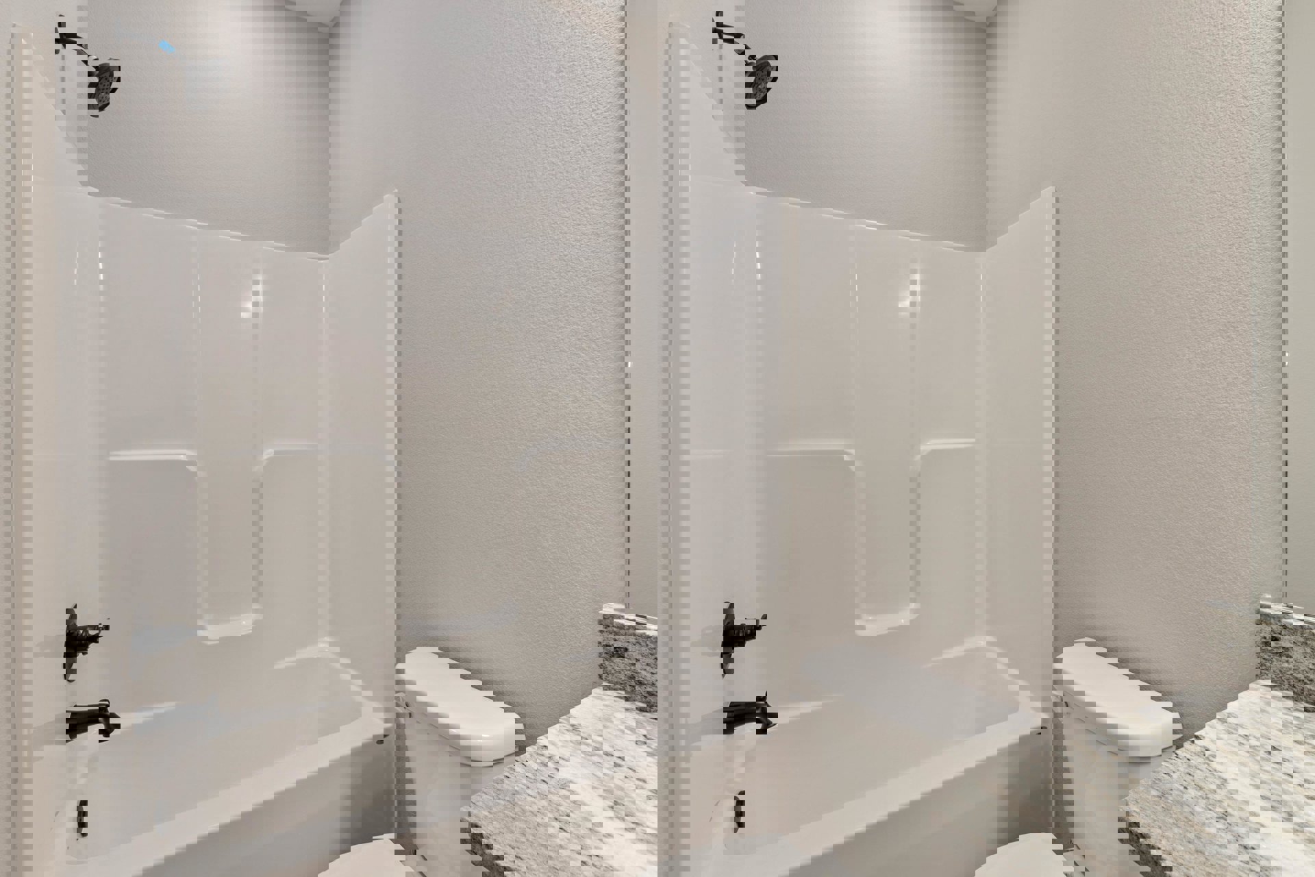 Bathroom with white bathtub and toilet, marble countertop, black metal shower fixture, light tile walls, and modern plumbing accessories