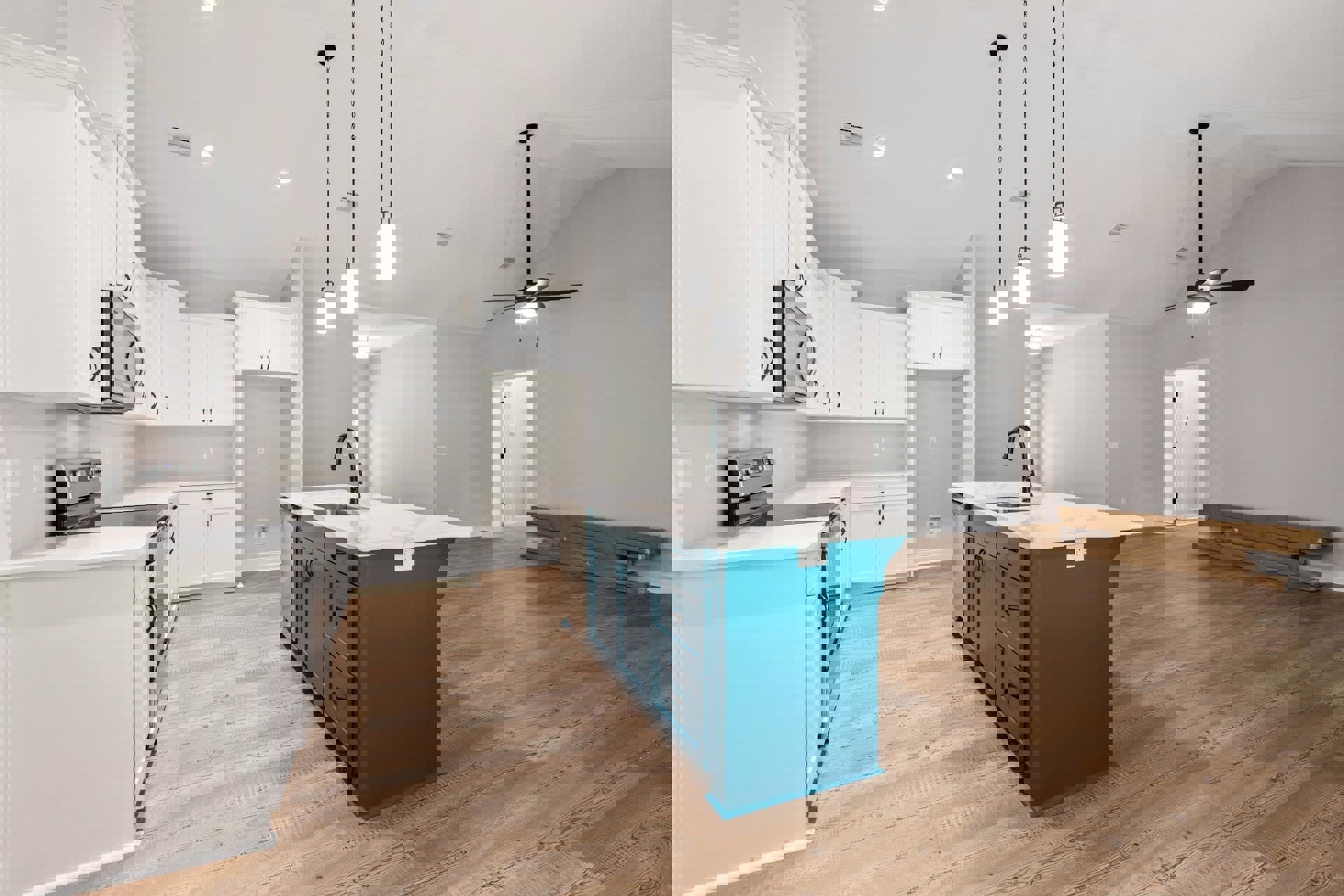 Blue kitchen island with built-in sink, white shaker cabinets, tile backsplash, stainless steel microwave, white quartz countertops, light fixture overhead, cardboard moving boxes