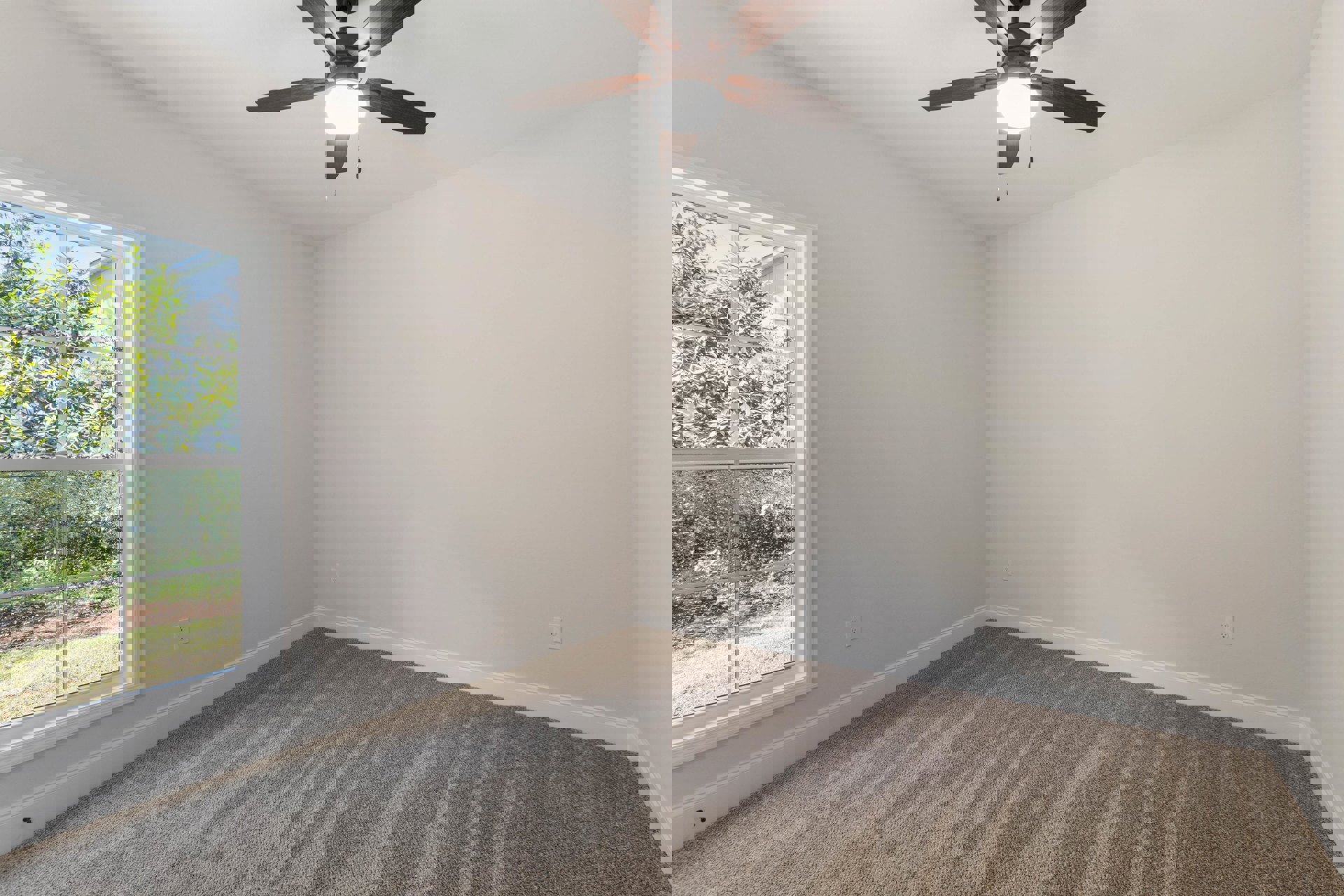 Carpeted room with white ceiling, ceiling fan with light fixture, multiple-pane window, neutral walls