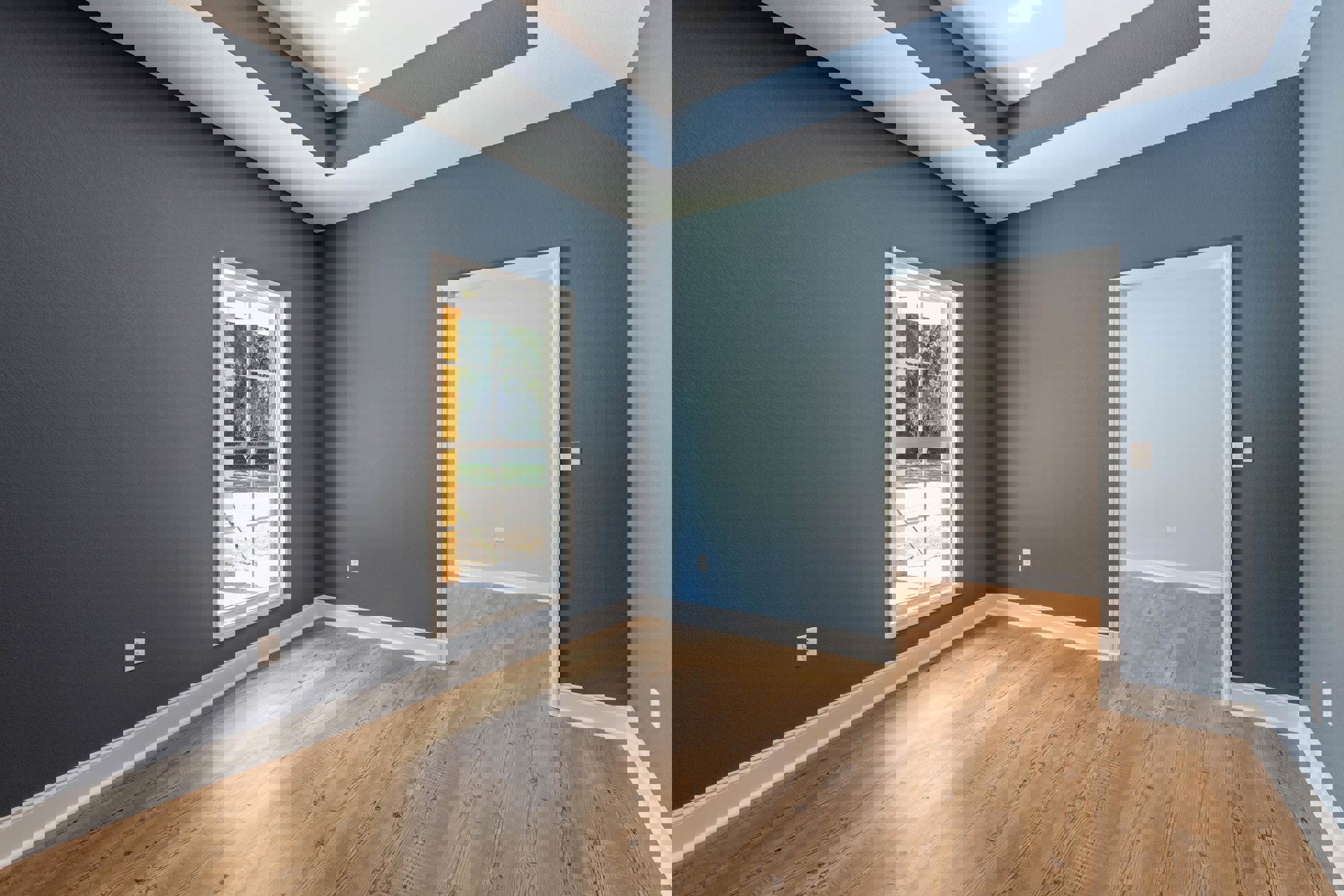 Corner of a room with white walls, white ceiling, wood laminate flooring, a white-framed window overlooking a yard, and a white door