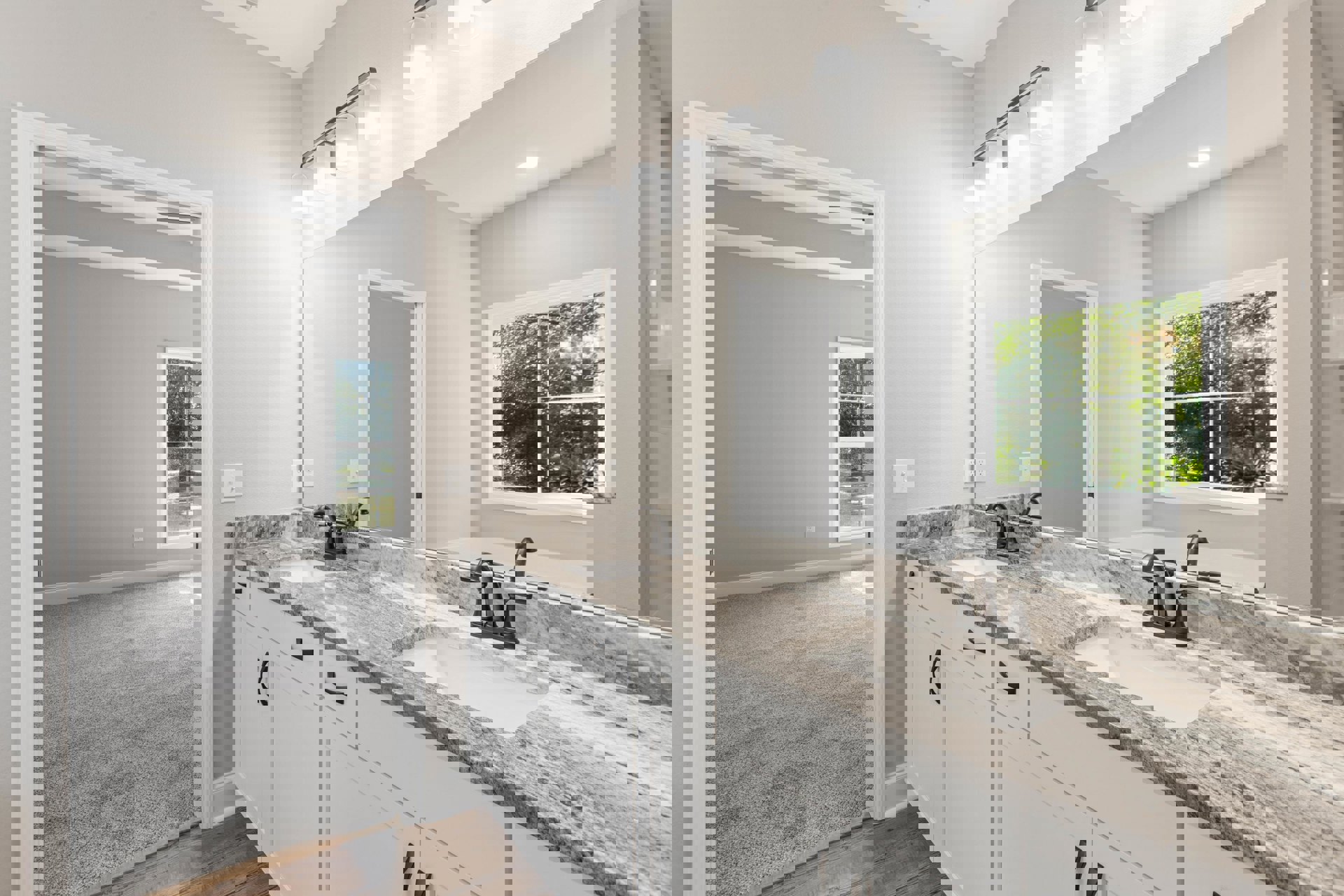 Bathroom with marble countertop, rectangular mirror above sink, white cabinetry, chrome faucet, window showing leafy trees, modern light fixture, freestanding white bathtub.