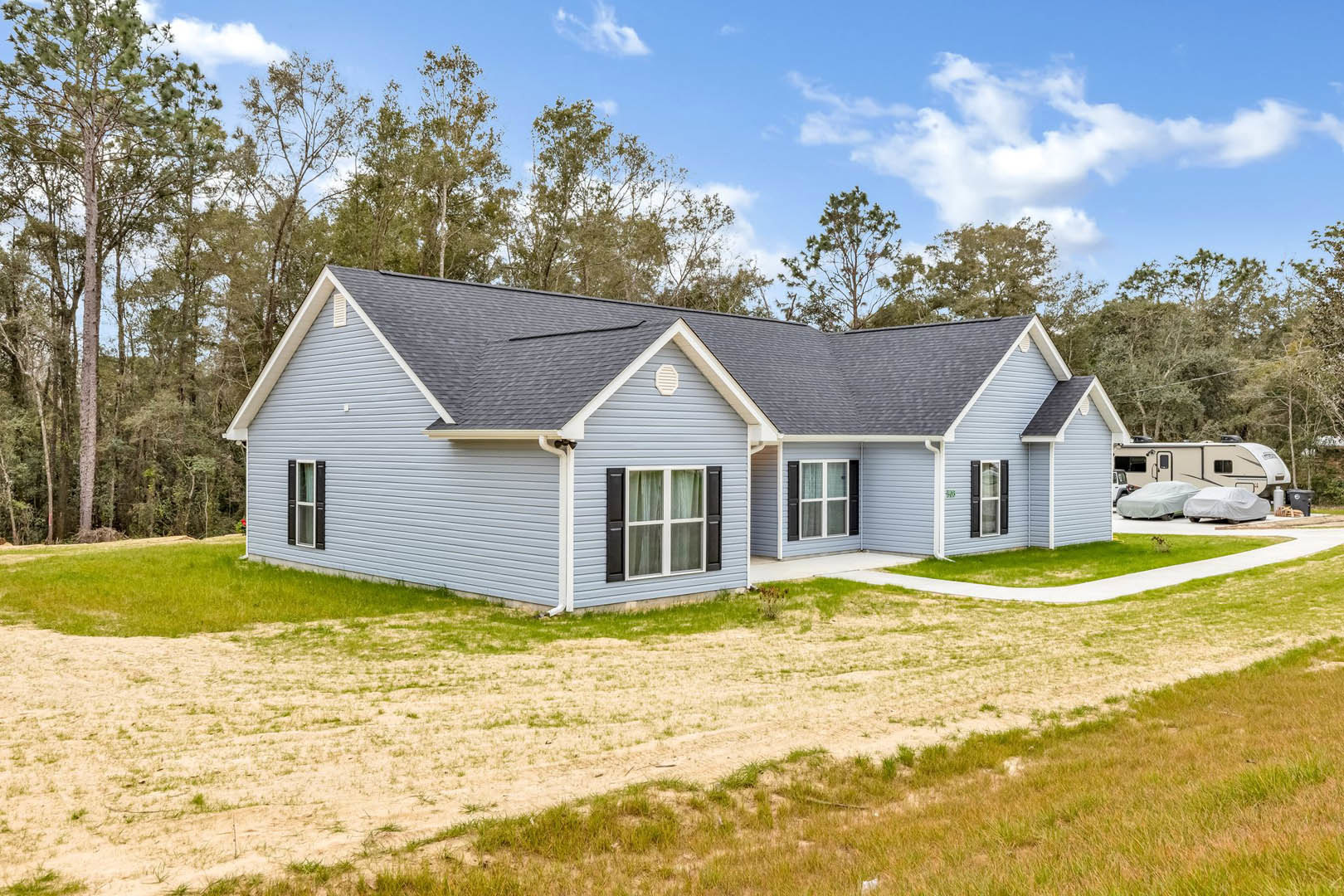 Two-story house with white siding, black shuttered windows, covered front porch, and driveway, surrounded by green lawn and mature trees, Robert Frost Farm visible in the