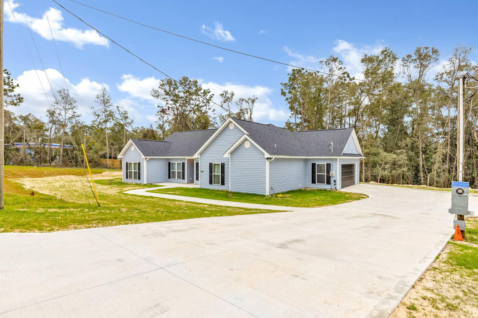 Two-story home with attached garage, concrete driveway, and mature trees behind the house