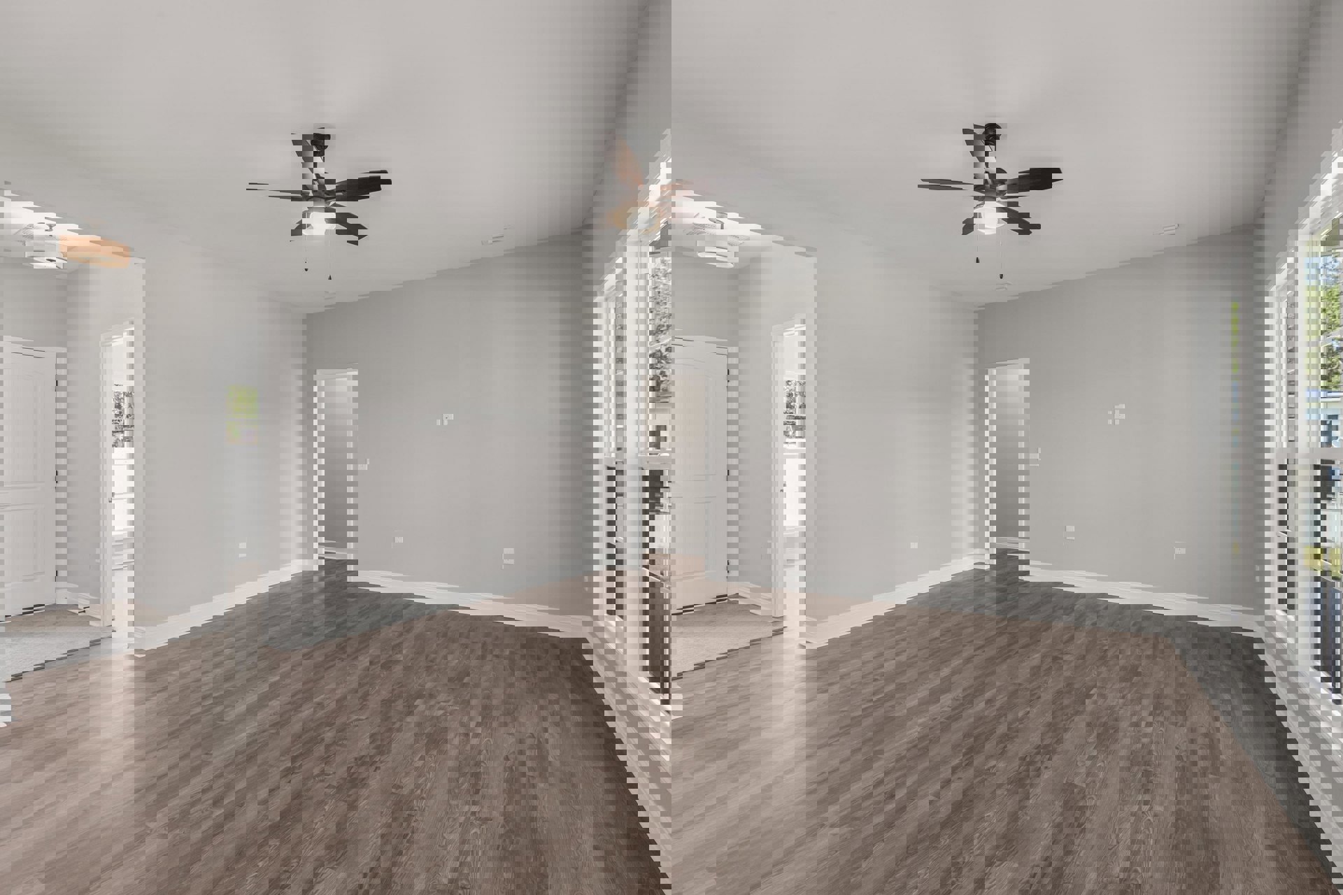 Ceiling fan with light fixture above hardwood floor, white walls, white door with black handles, and white door frame