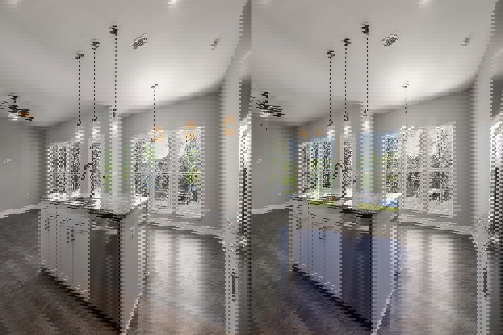 Modern kitchen with white cabinetry, central island featuring an undermount sink, stainless steel dishwasher, light countertops, and large window overlooking trees