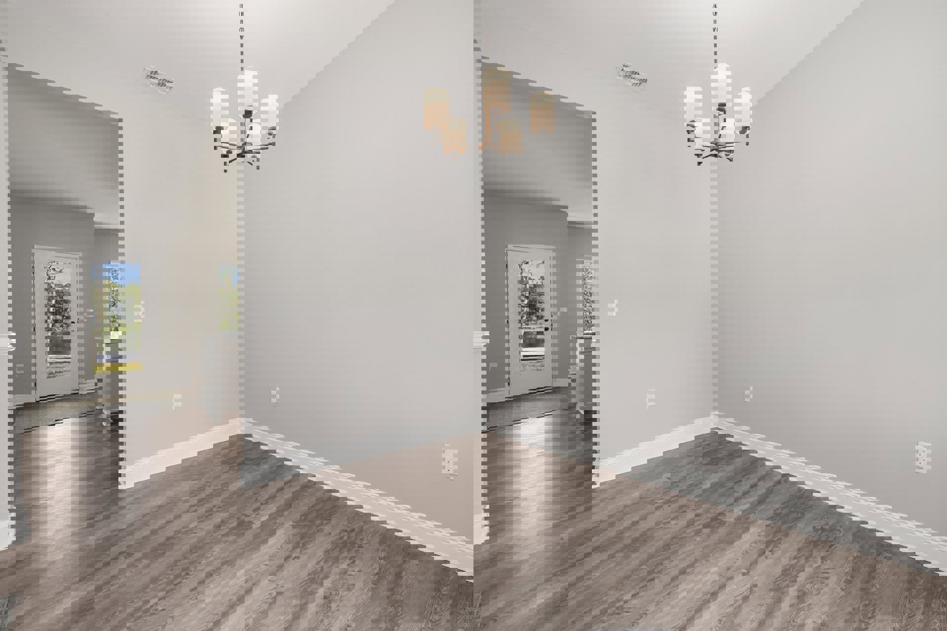 Chandelier hanging from white ceiling above hardwood floor, white baseboards, large windows and glass door with lake view, white electrical outlet, modern lamp with white shade