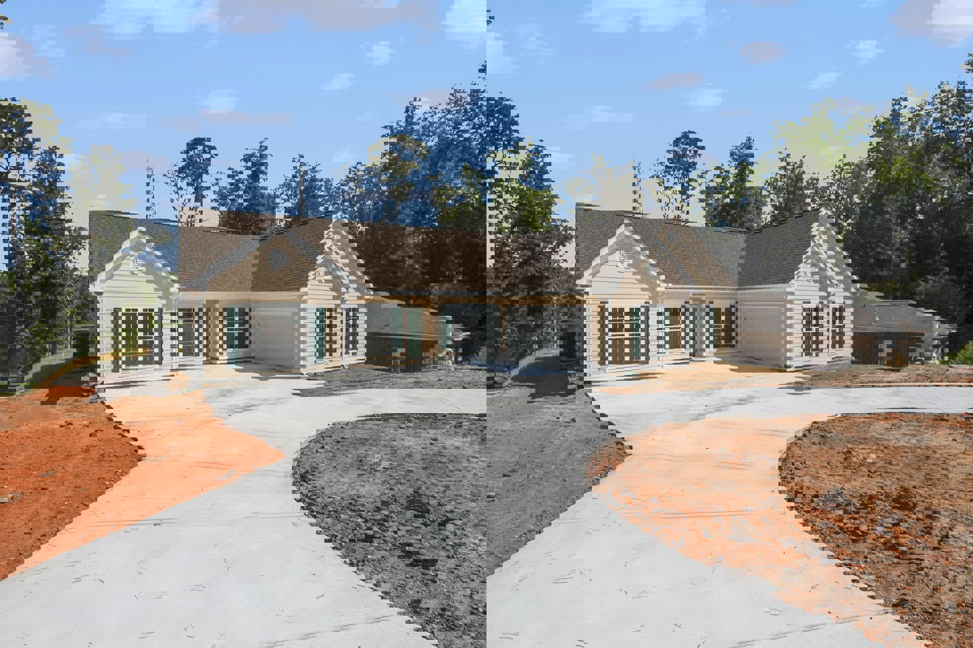 Two-story home with white siding, black-framed windows, attached garage, concrete driveway, and landscaped front yard with small trees and shrubs