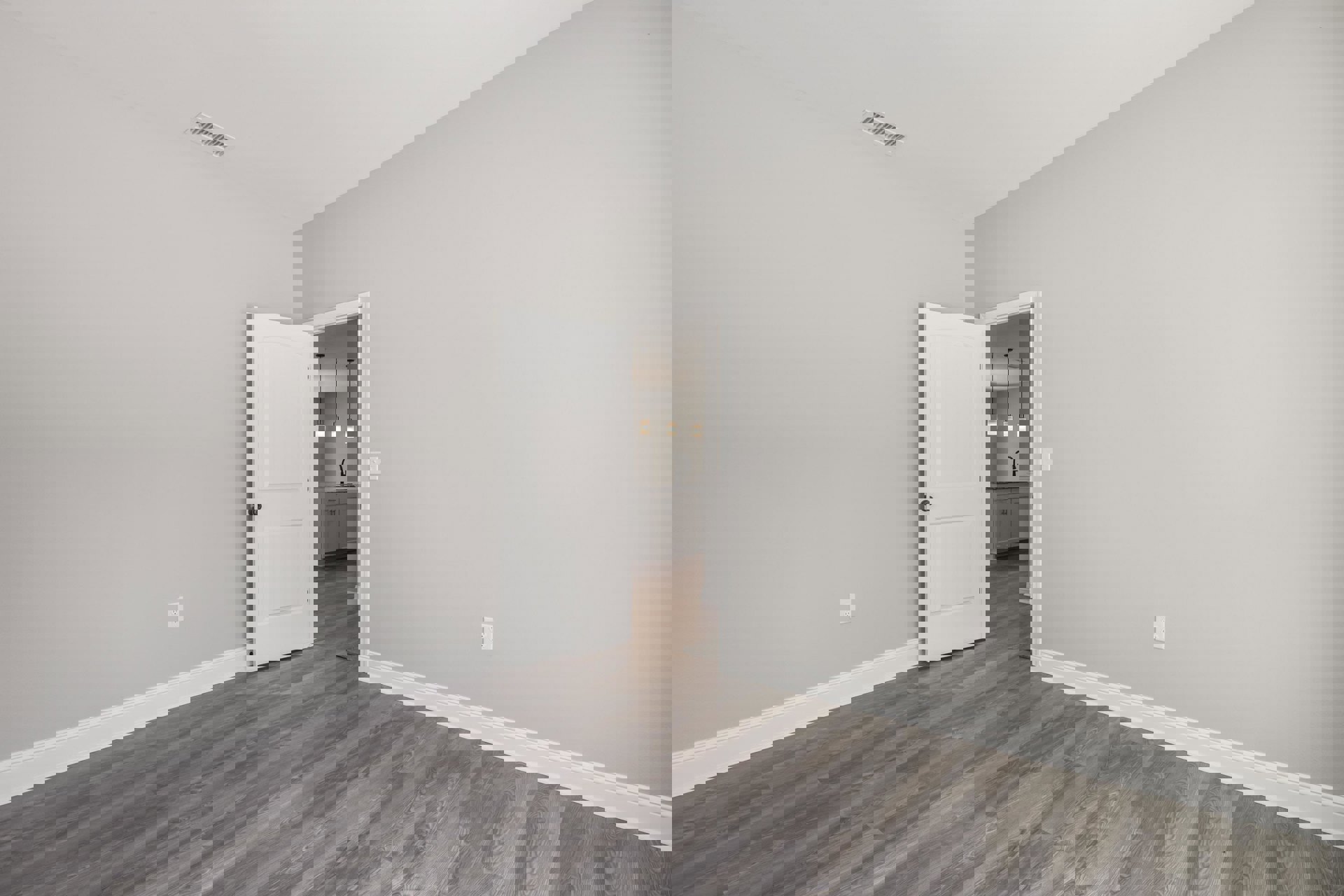 White paneled door with black knob open to reveal bathroom with three ceiling lights, wood flooring, white baseboards, ceiling vent, and smooth plaster walls