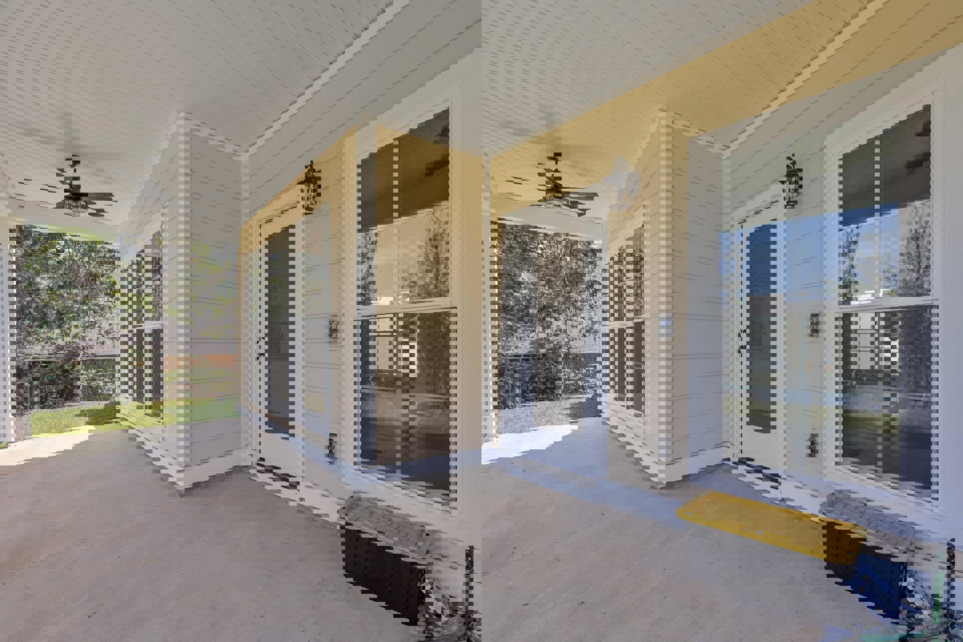 Covered porch with yellow walls, white ceiling, glass door, black and yellow storage bin, and wall-mounted lamp