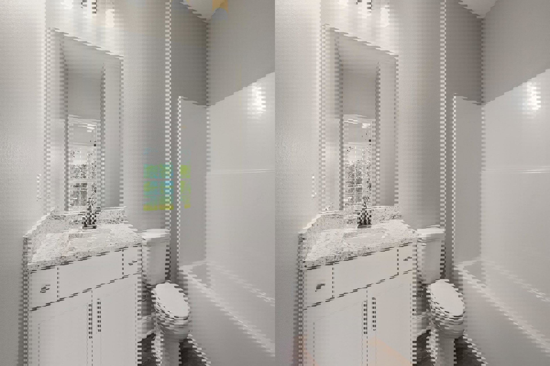 Modern bathroom featuring a freestanding white bathtub, white toilet with closed lid, light wood cabinetry, stone countertop, and large window offering lake views