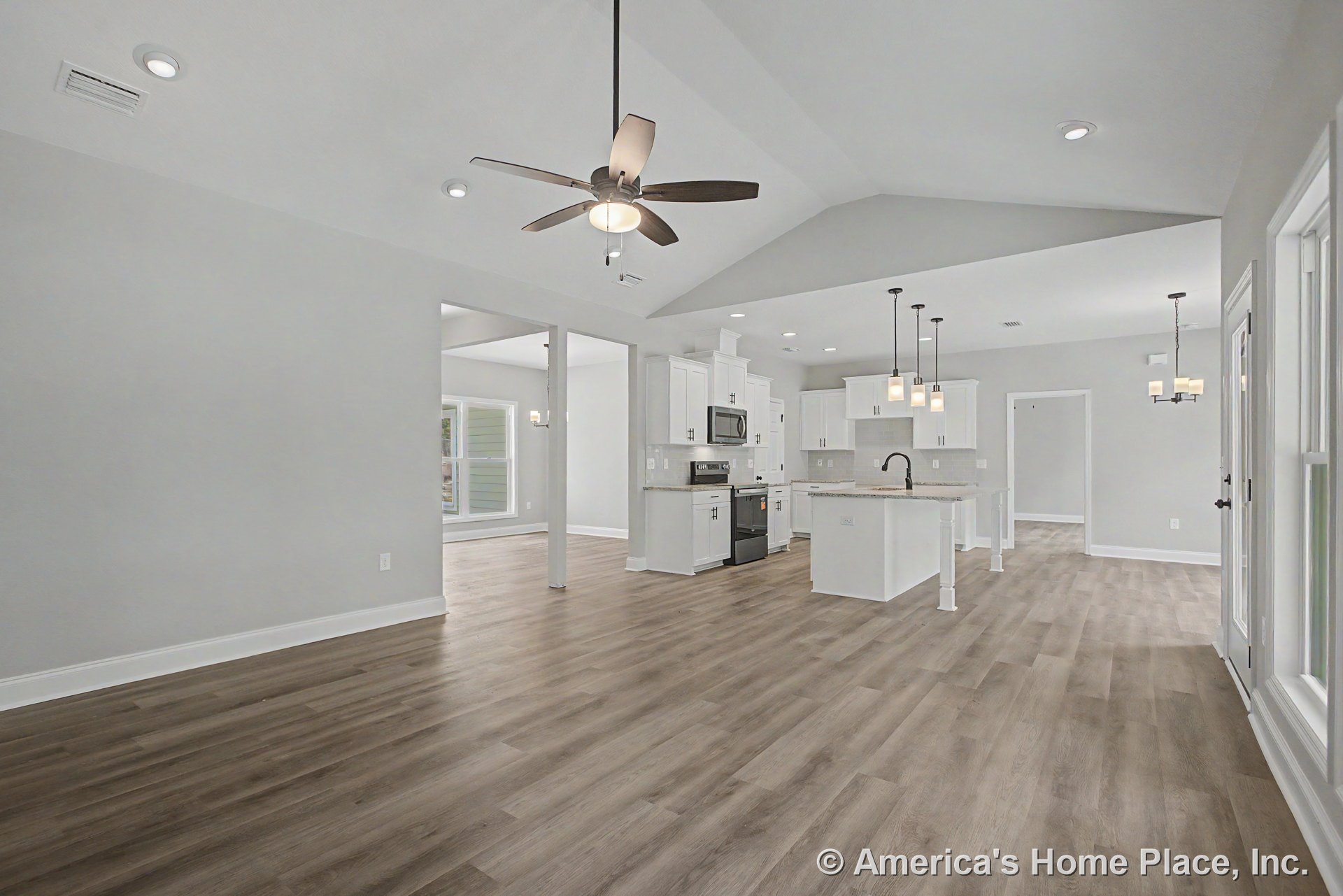 Open-concept kitchen and living area with vaulted ceiling, recessed lighting, ceiling fan, white shaker cabinets, granite island with pendant lights, wood-look flooring, and large