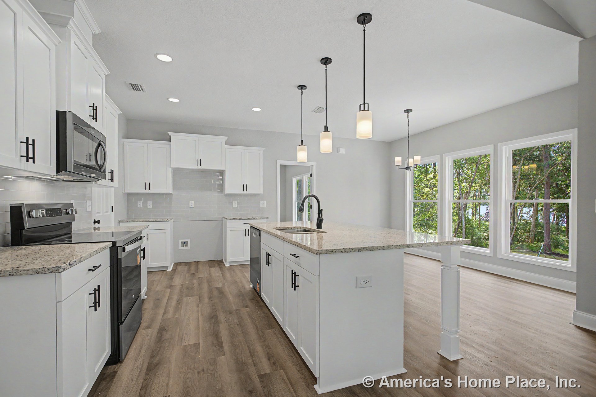 White shaker cabinets with granite countertops, subway tile backsplash, and stainless appliances; central island beneath pendant and recessed lighting; large windows and wood-look