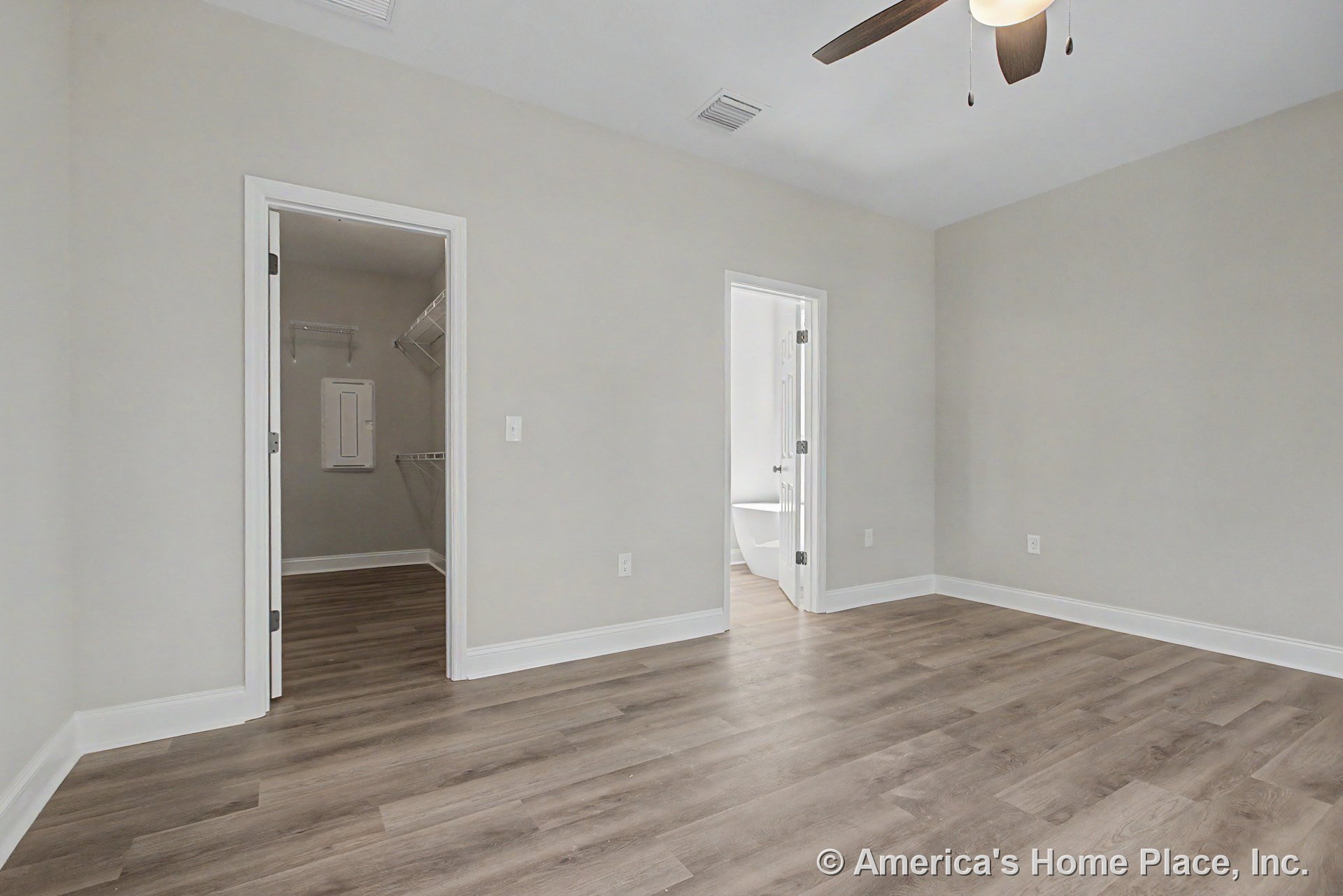 Bedroom with wood-look plank flooring, ceiling fan and light fixture, white trim and baseboards, neutral wall color, walk-in closet featuring wire shelving, and bathroom entry
