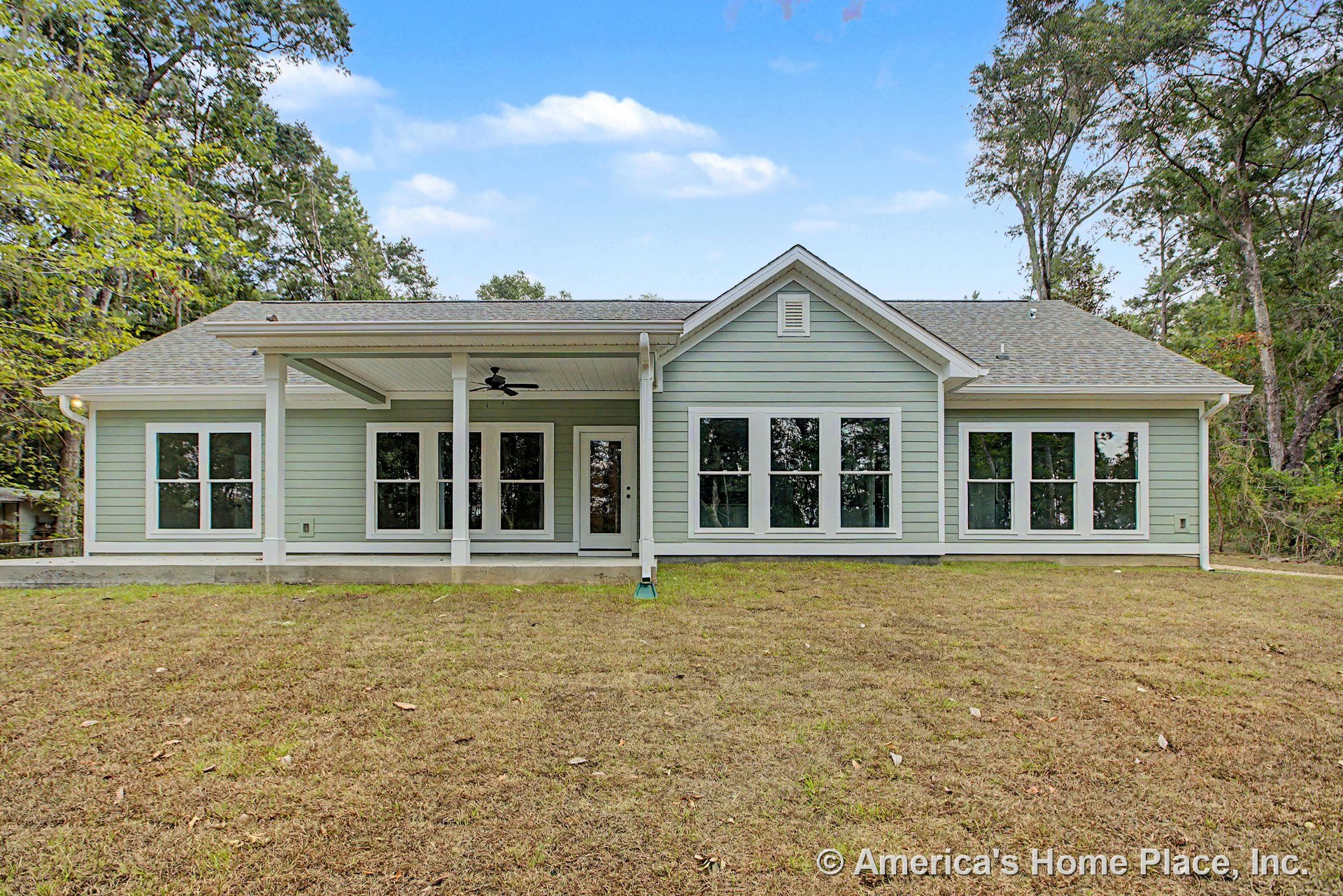 Covered rear porch with ceiling fan, multiple large windows, lap siding exterior, gable roof, and white trim detailing.