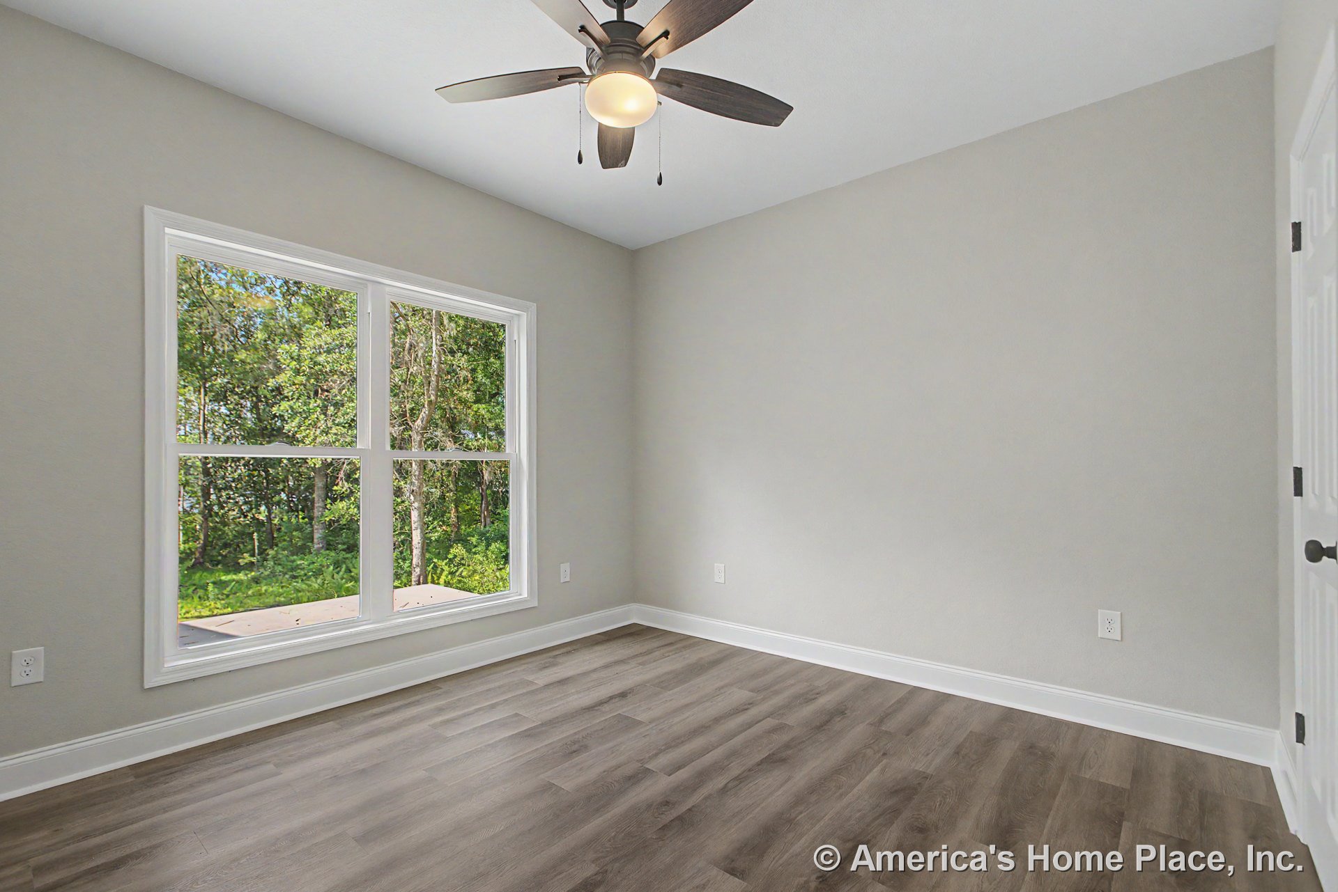 Bedroom with large double windows framed in white trim, light gray painted walls, wood-look vinyl plank flooring, white baseboards, ceiling fan with integrated light, and white
