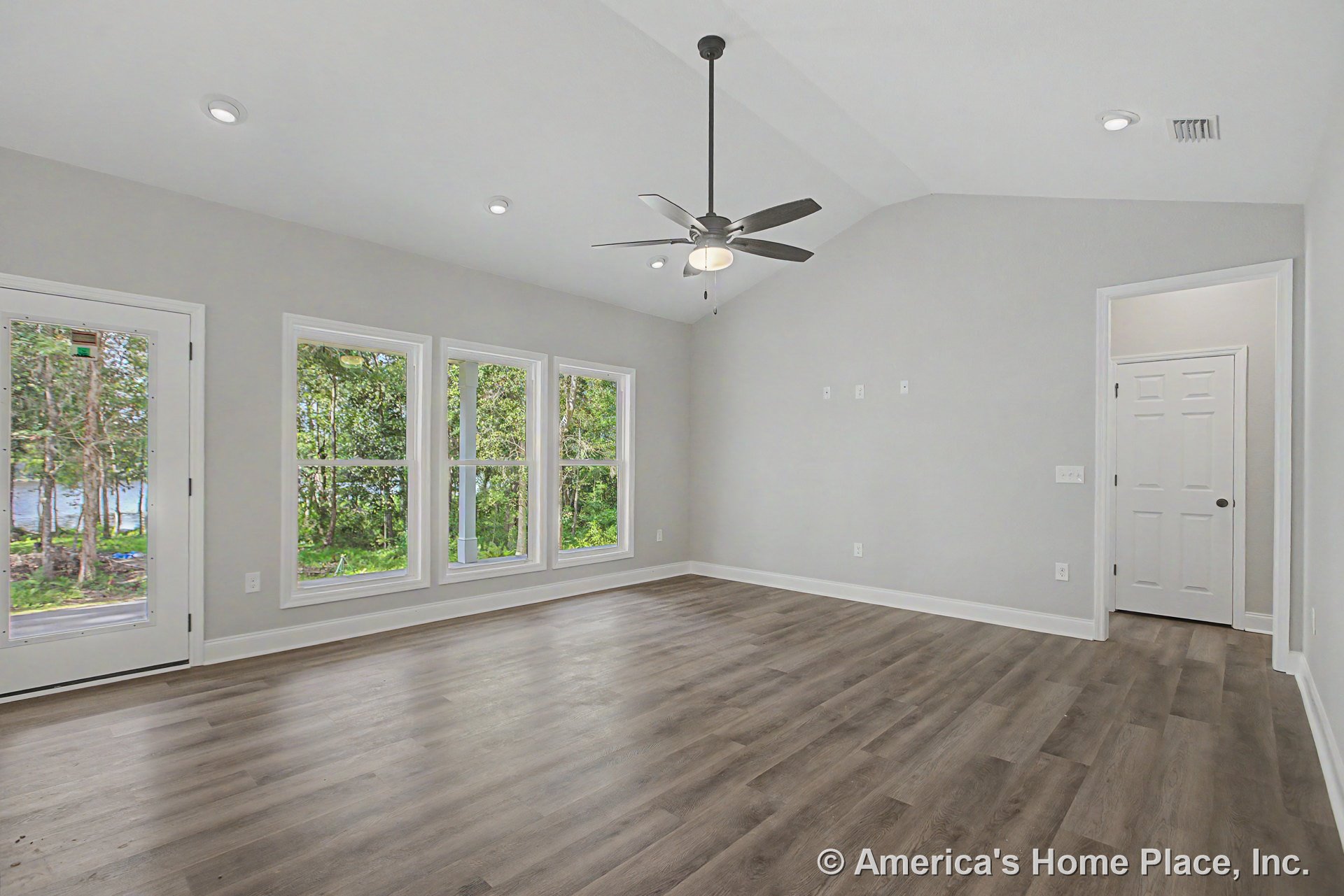 Vaulted ceiling with recessed lighting and ceiling fan, expansive window wall allowing natural light, wood-look plank flooring, white trim and baseboards, neutral wall color