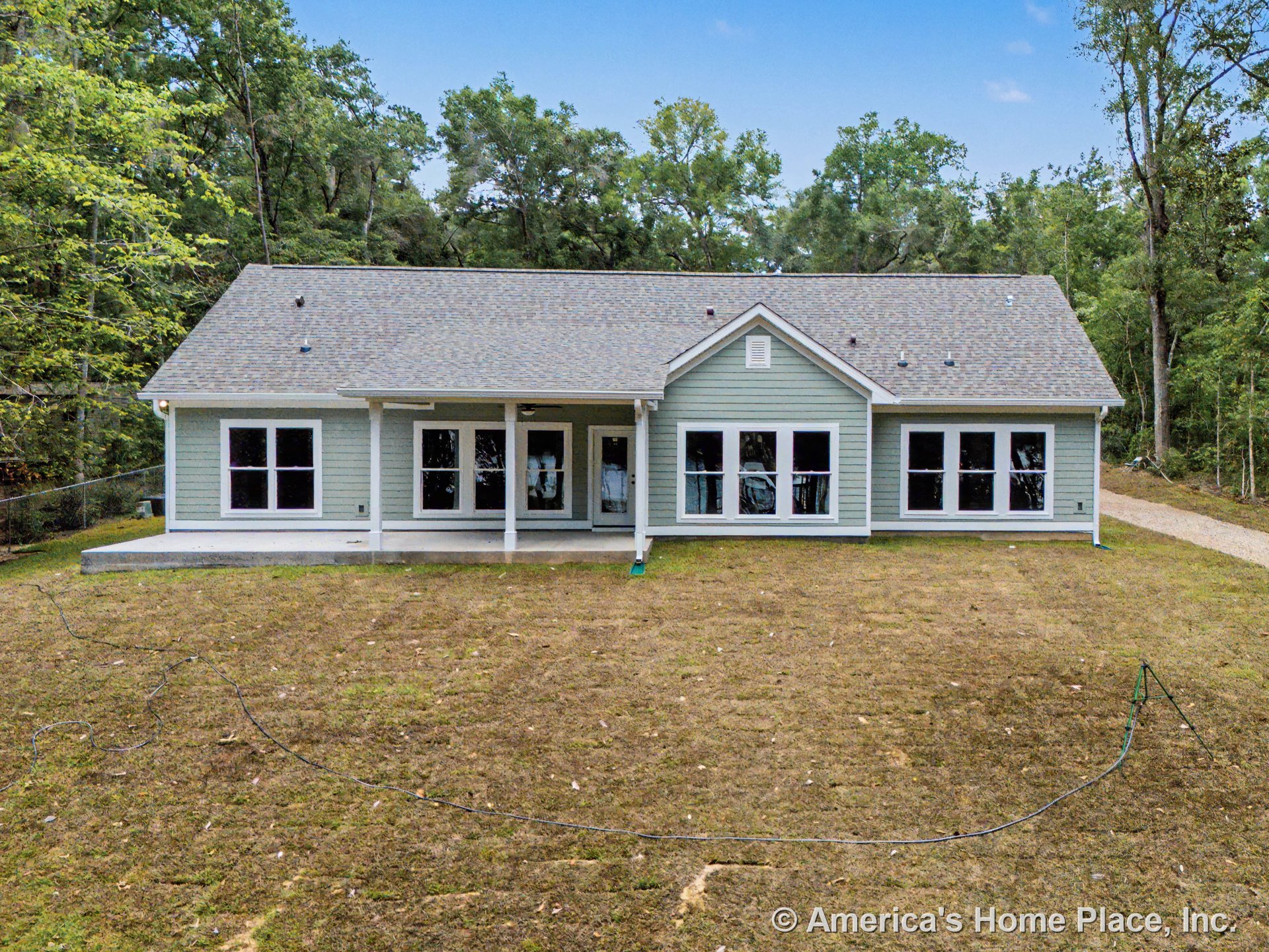Covered rear porch with ceiling light, gray horizontal lap siding, multiple double-hung windows with white trim, gable roof with asphalt shingles, concrete porch foundation
