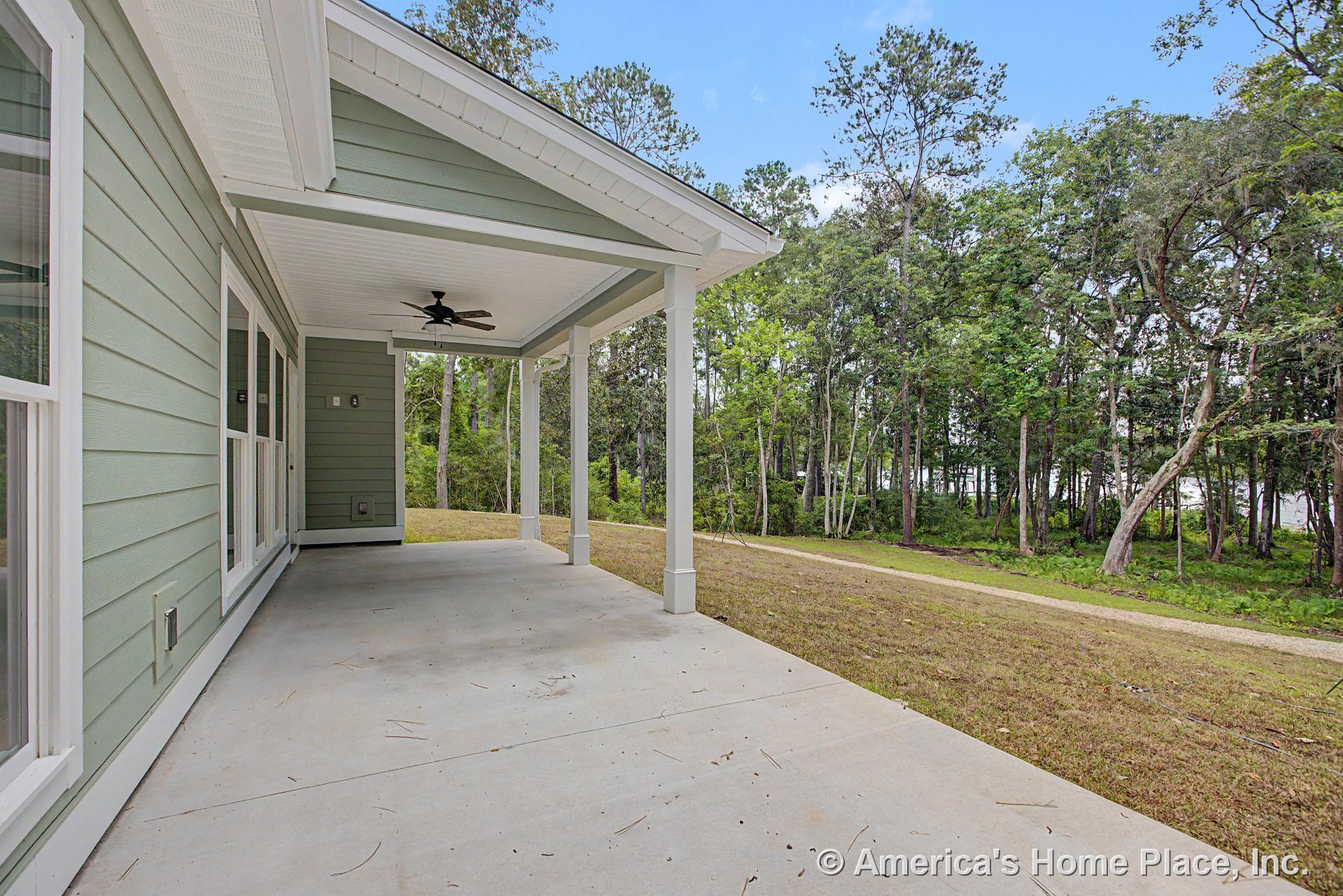 Covered porch with concrete flooring, ceiling fan, white trim, green horizontal siding, large windows, and column supports.