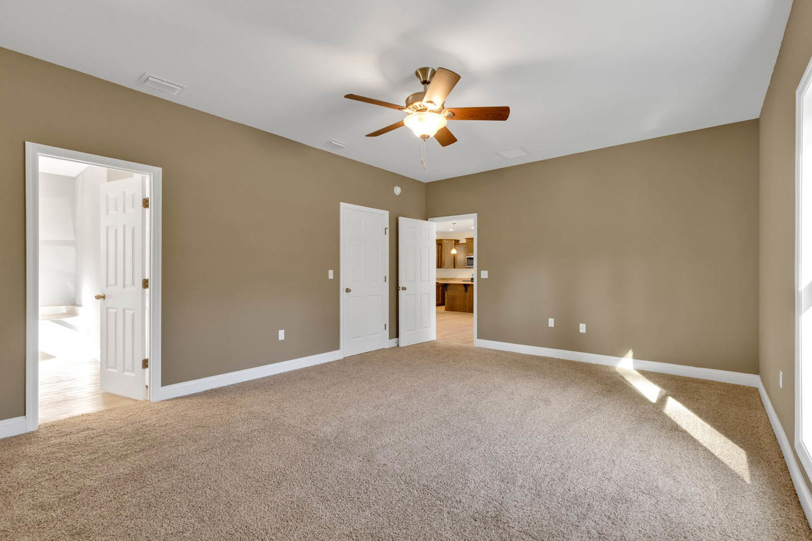 Carpeted room with white walls, ceiling fan and light fixture, white door featuring gold handle, plaster ceiling