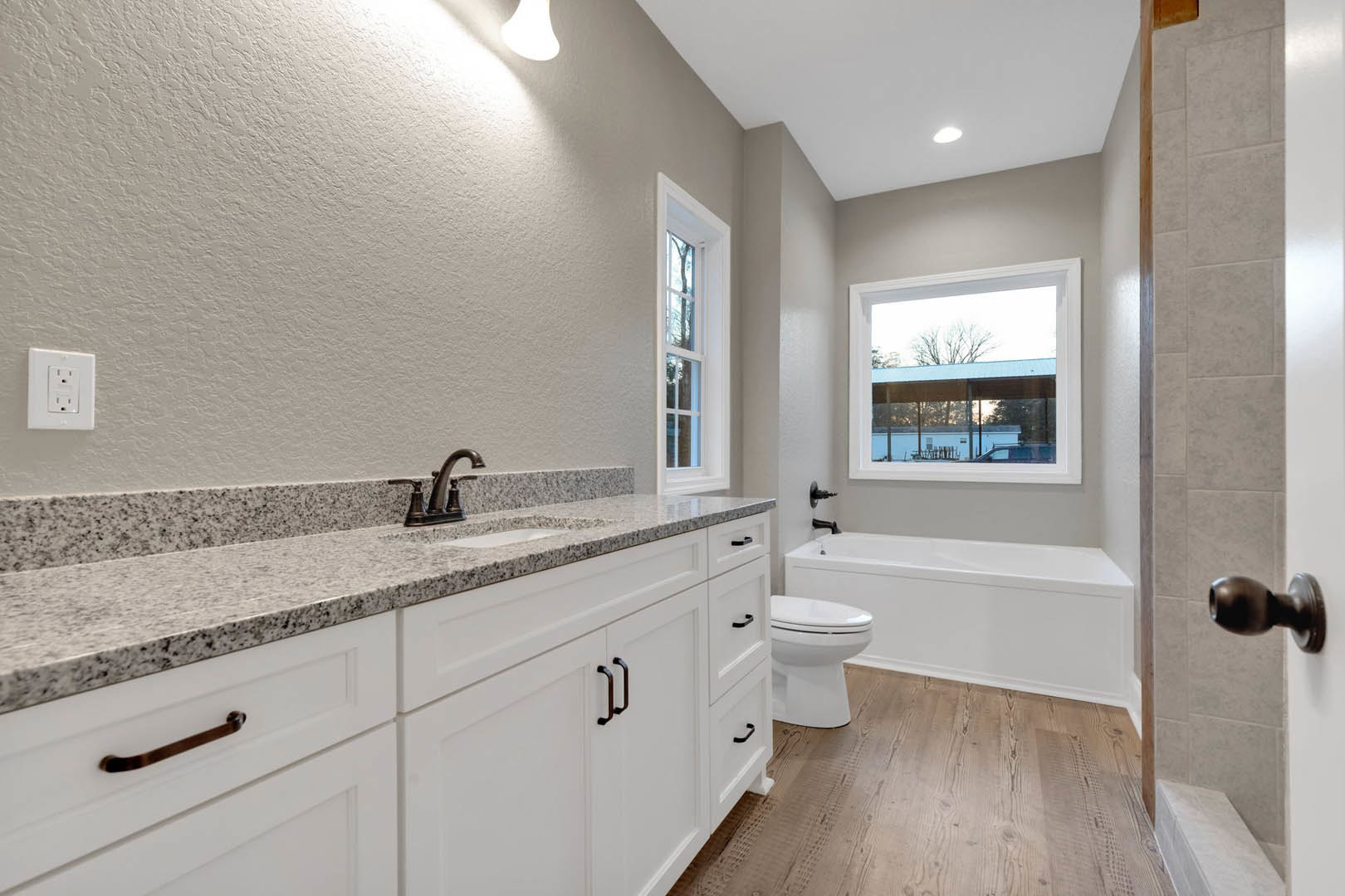 Modern bathroom featuring a freestanding white tub, rectangular sink set in a stone countertop, tile flooring, and light wood cabinetry