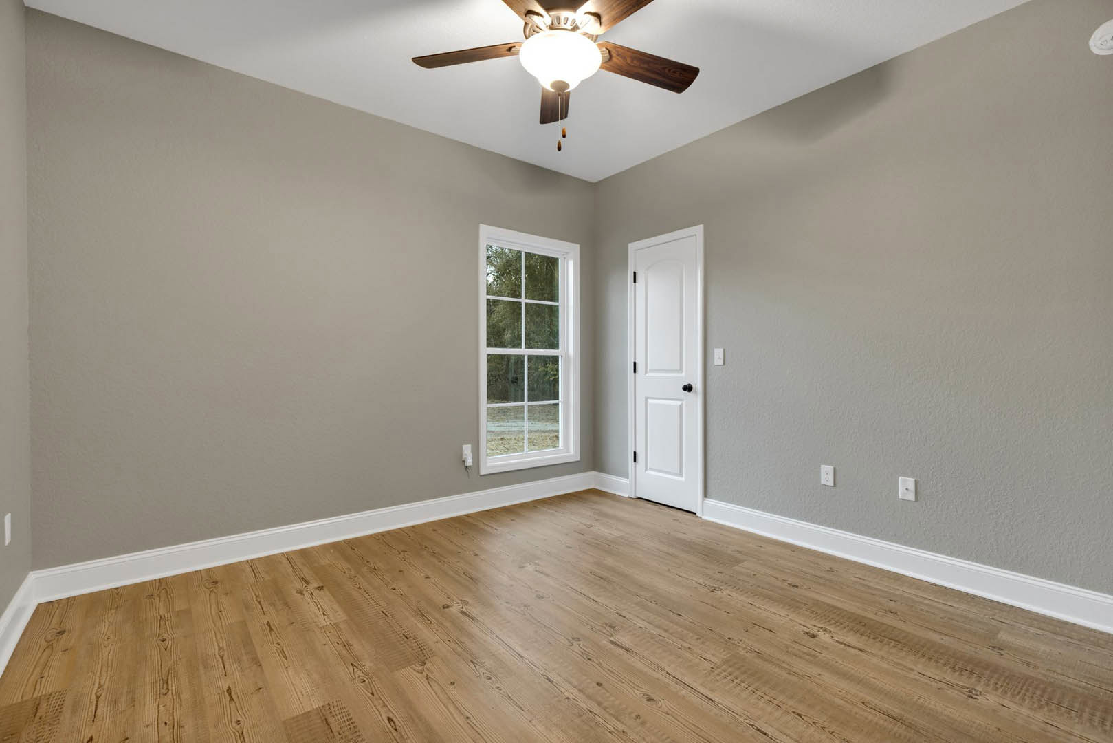 Ceiling fan with light fixture, white walls with plaster molding, large window, wood laminate flooring, white door