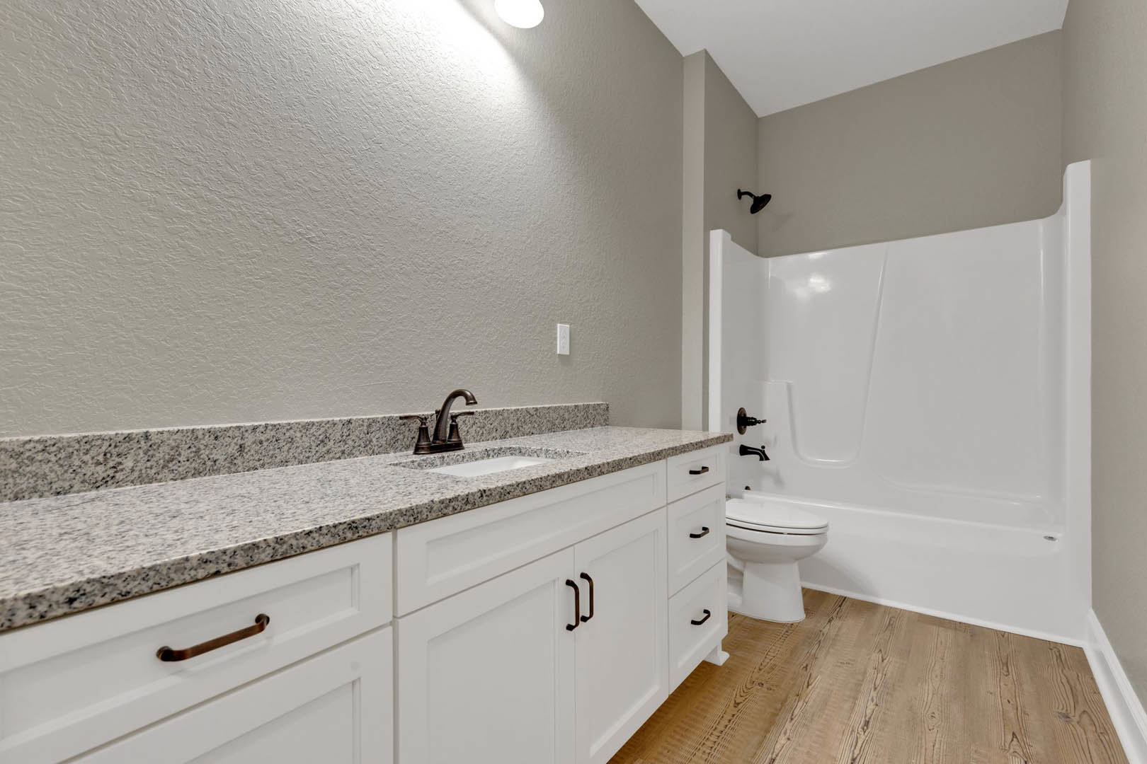 Modern bathroom featuring a white porcelain sink with chrome faucet, white toilet, light wood flooring, and neutral tile walls.
