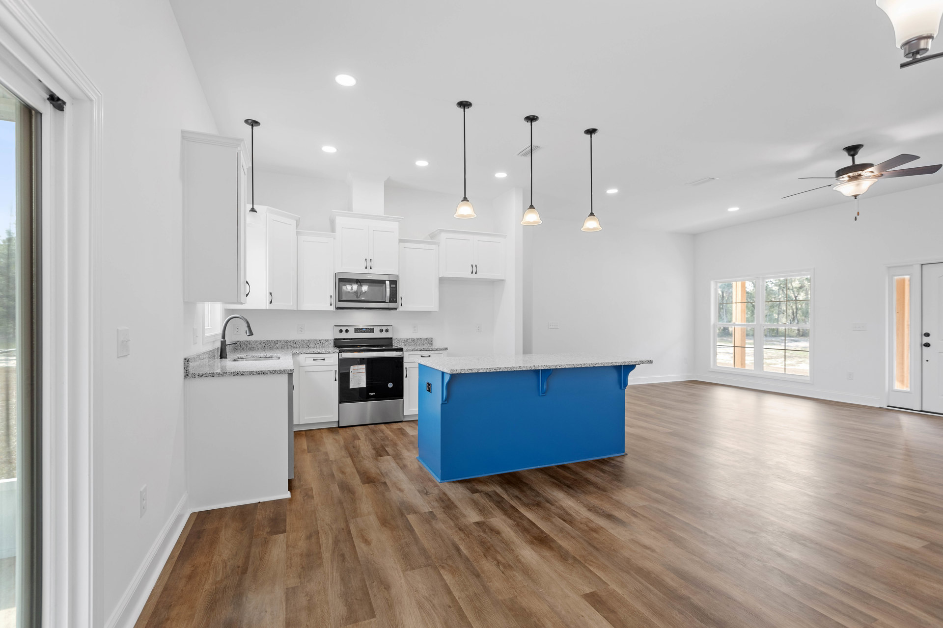 Blue kitchen island with white quartz countertop, white shaker cabinets, stainless steel appliances, wood laminate flooring, modern pendant light, built-in microwave, paper taped