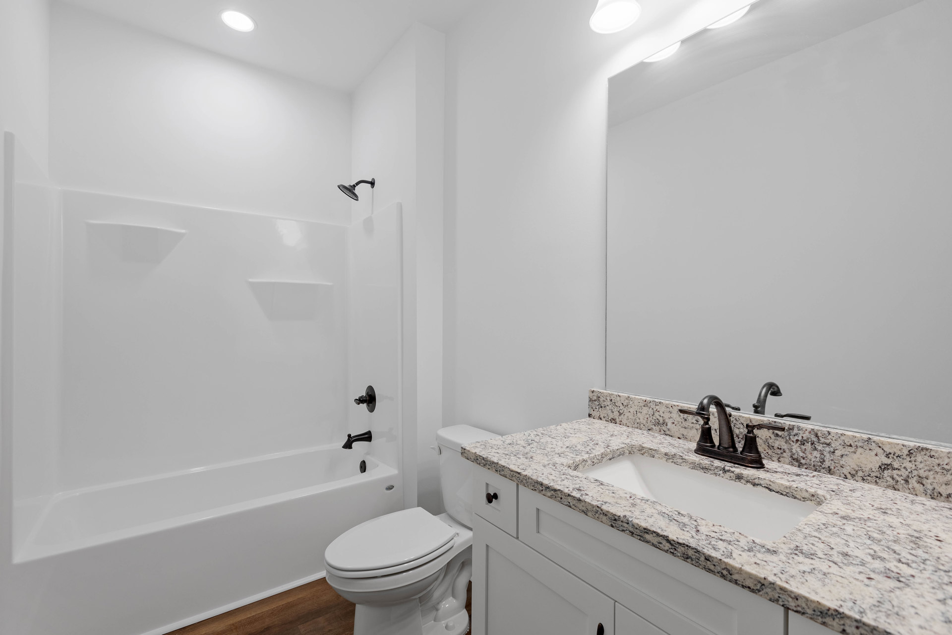 Bathroom with white toilet, rectangular sink and chrome faucet, light tile flooring, wall-mounted mirror, and white cabinetry