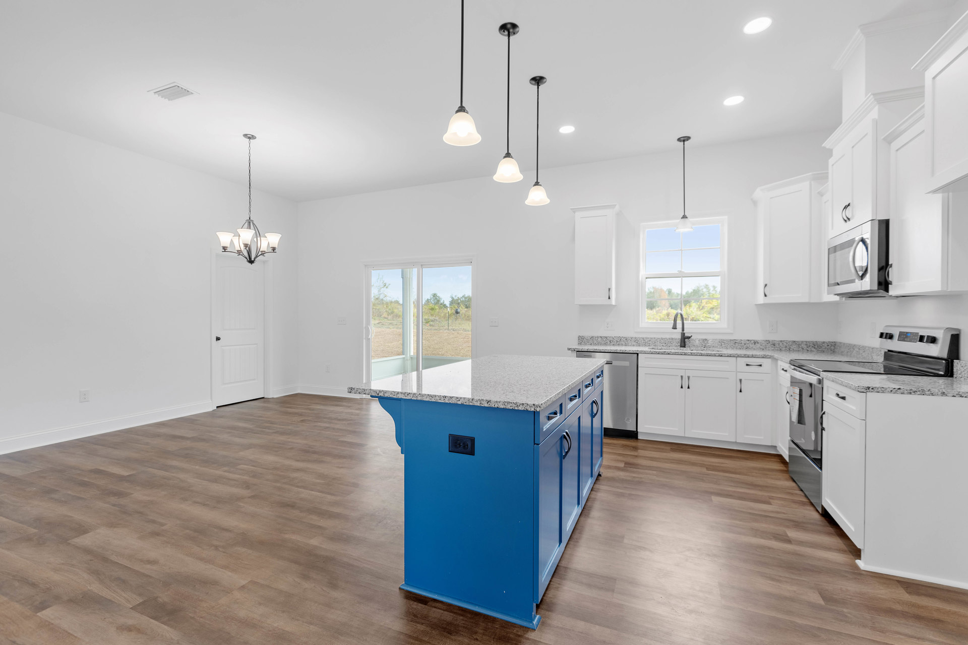 Blue kitchen island with white marble countertop, surrounded by white cabinetry, stainless steel appliances, and light wood flooring