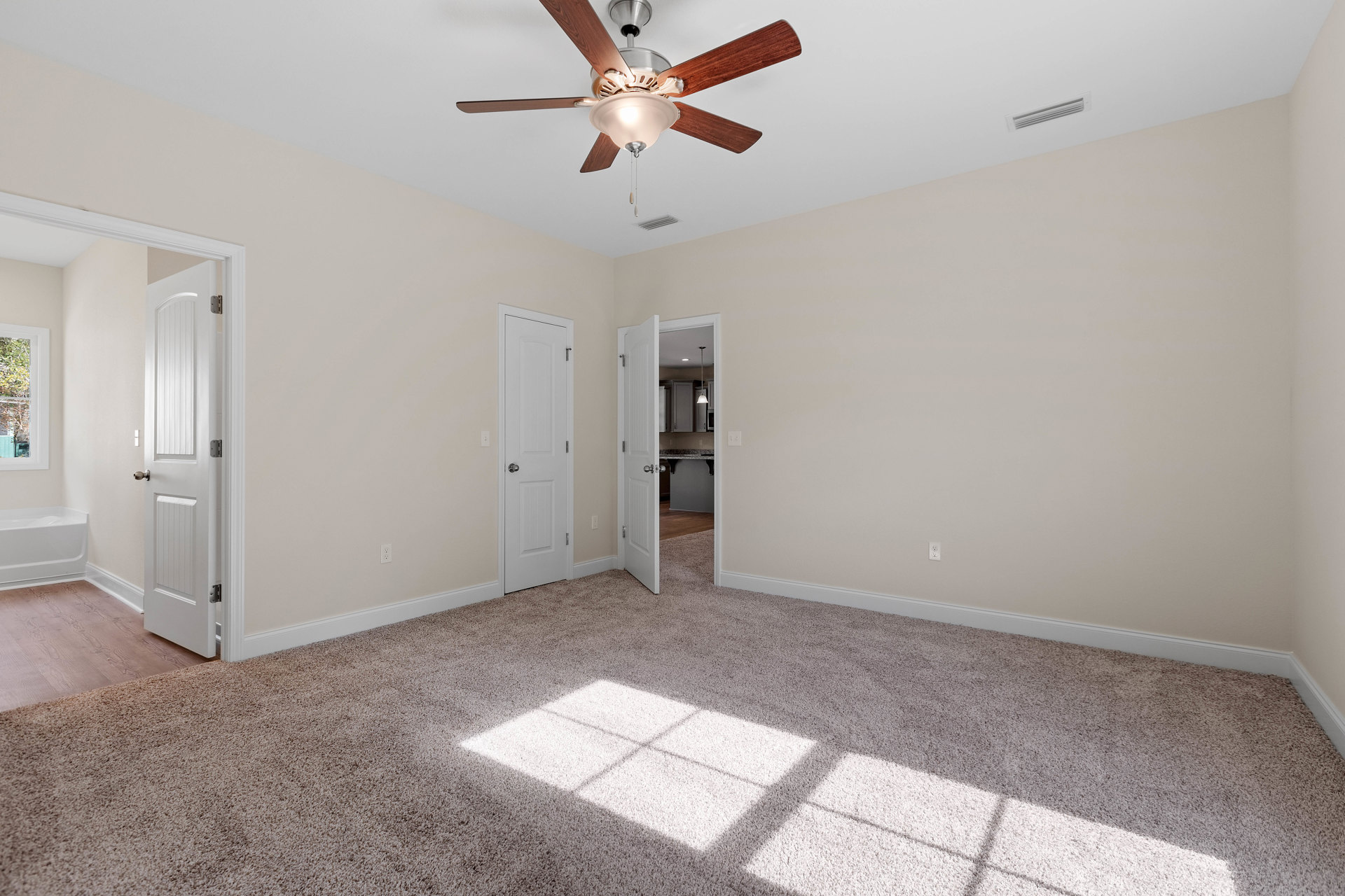 Ceiling fan with light fixture mounted on white ceiling above carpeted floor, white door with silver knob open to adjacent room