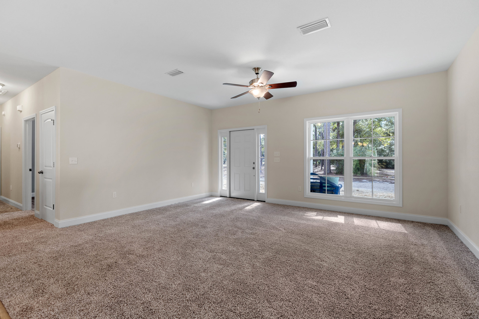 Carpeted room with white glass-paneled door, ceiling fan with light fixture, window featuring exterior bench, and ceiling vent
