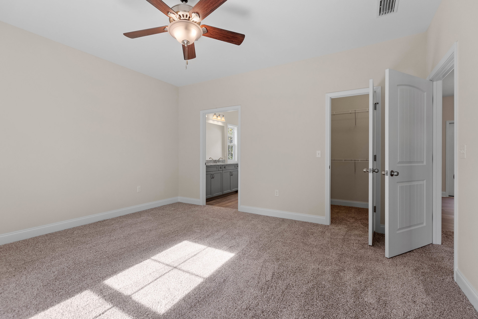Bedroom with light gray walls, ceiling fan with integrated light, white paneled closet doors, and wood-look flooring