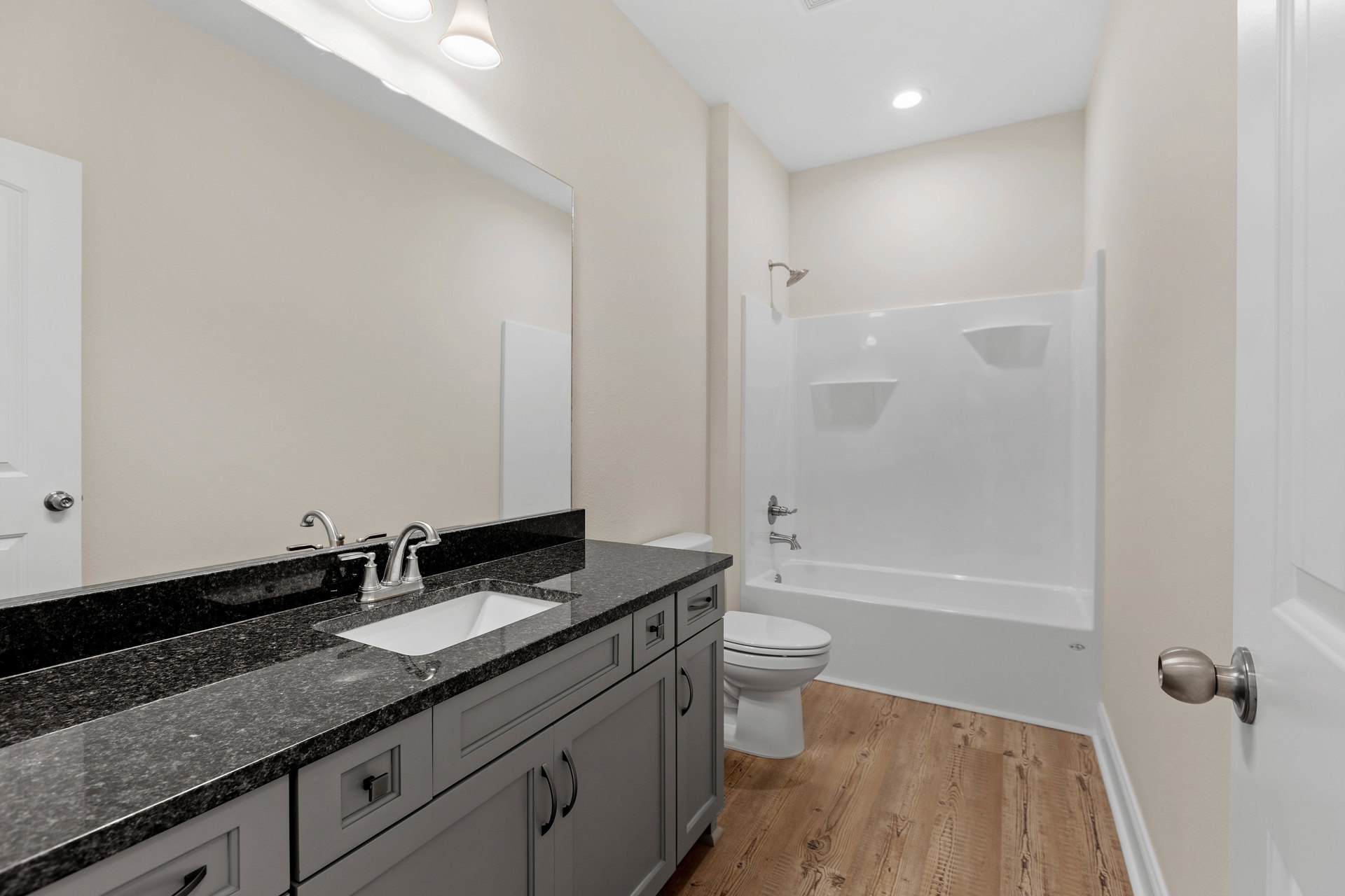 Bathroom with white toilet, granite countertop sink, tile flooring, and white cabinetry