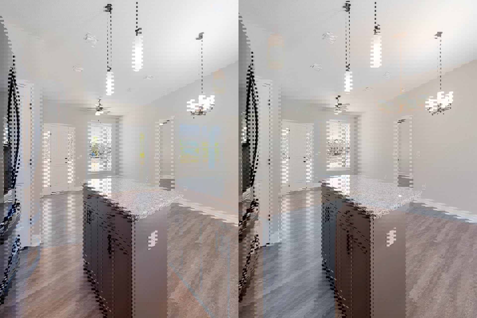 Granite kitchen island with black handles, white cabinetry, built-in sink, white electrical outlet on wall, glass-paneled door, and overhead lighting fixtures