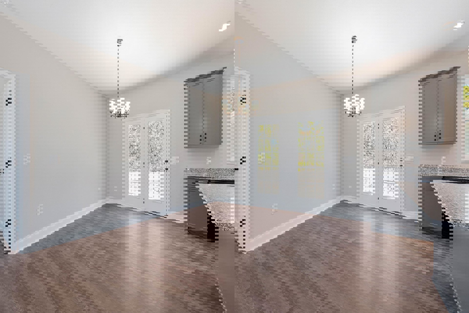 Wood flooring and white walls in a spacious room, double glass-paneled doors, grey cabinetry against a white wall, chandelier overhead, close-up of a countertop, hinged door