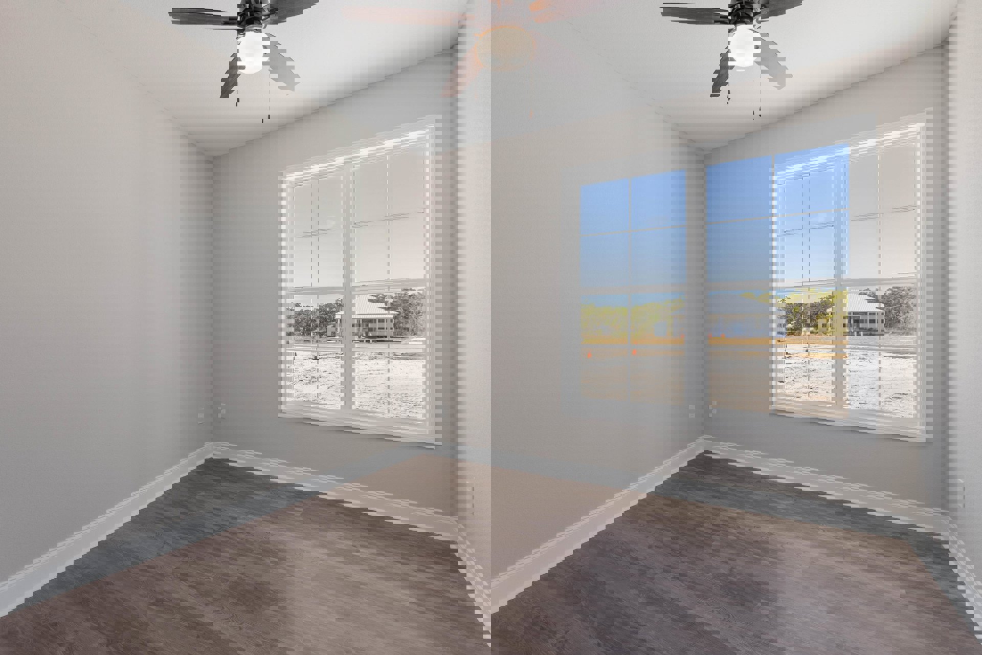 Wood floor room with white plaster walls, ceiling fan with light, large window showing neighboring house.