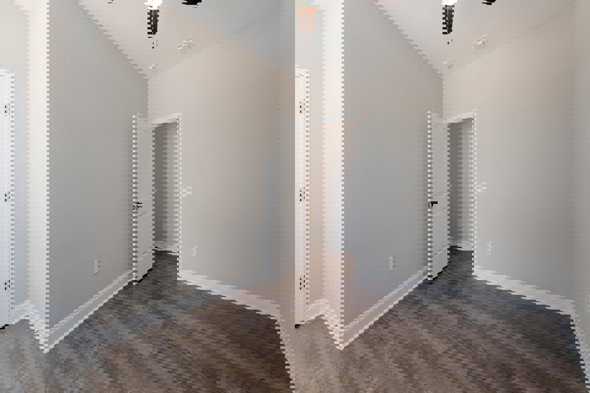 White paneled door with silver hinge, wood laminate flooring, white walls, ceiling fan, and light switch visible in a residential room.