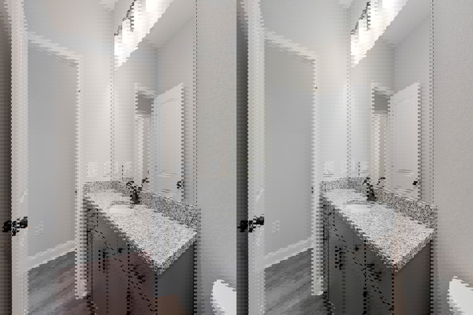Bathroom featuring a marble countertop with an undermount sink, large framed mirror above, white cabinetry, black hardware, and tiled walls.