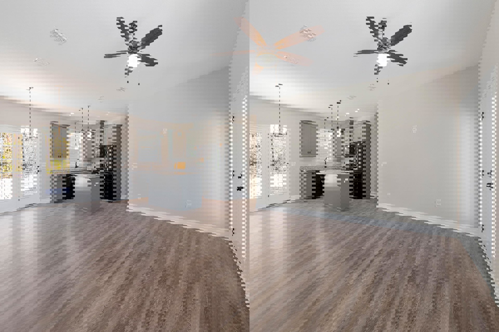 Open-concept kitchen and living room with wood flooring, ceiling fan with light, white door featuring glass panels and black knobs, plaster walls, and modern finishes