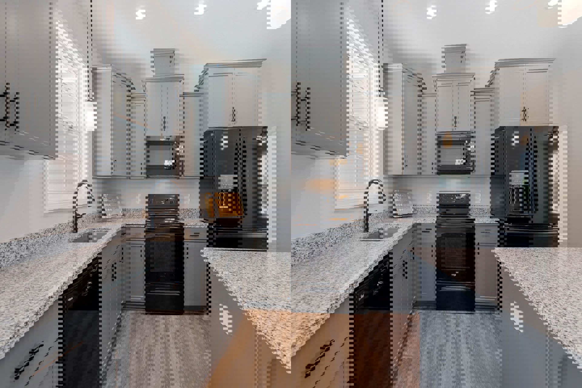 Granite countertops, black stove and refrigerator, built-in microwave with lights on, wooden cutting board with a bow, close-up of dishwasher, wood cabinetry and stainless steel