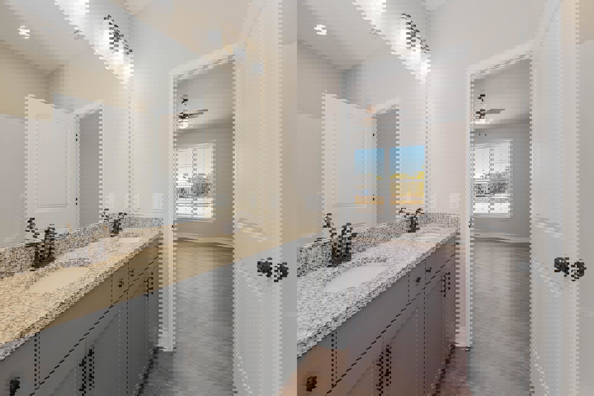 Bathroom with marble countertop, wood flooring, white cabinetry, undermount sink, chrome faucet, and a white door with curved top