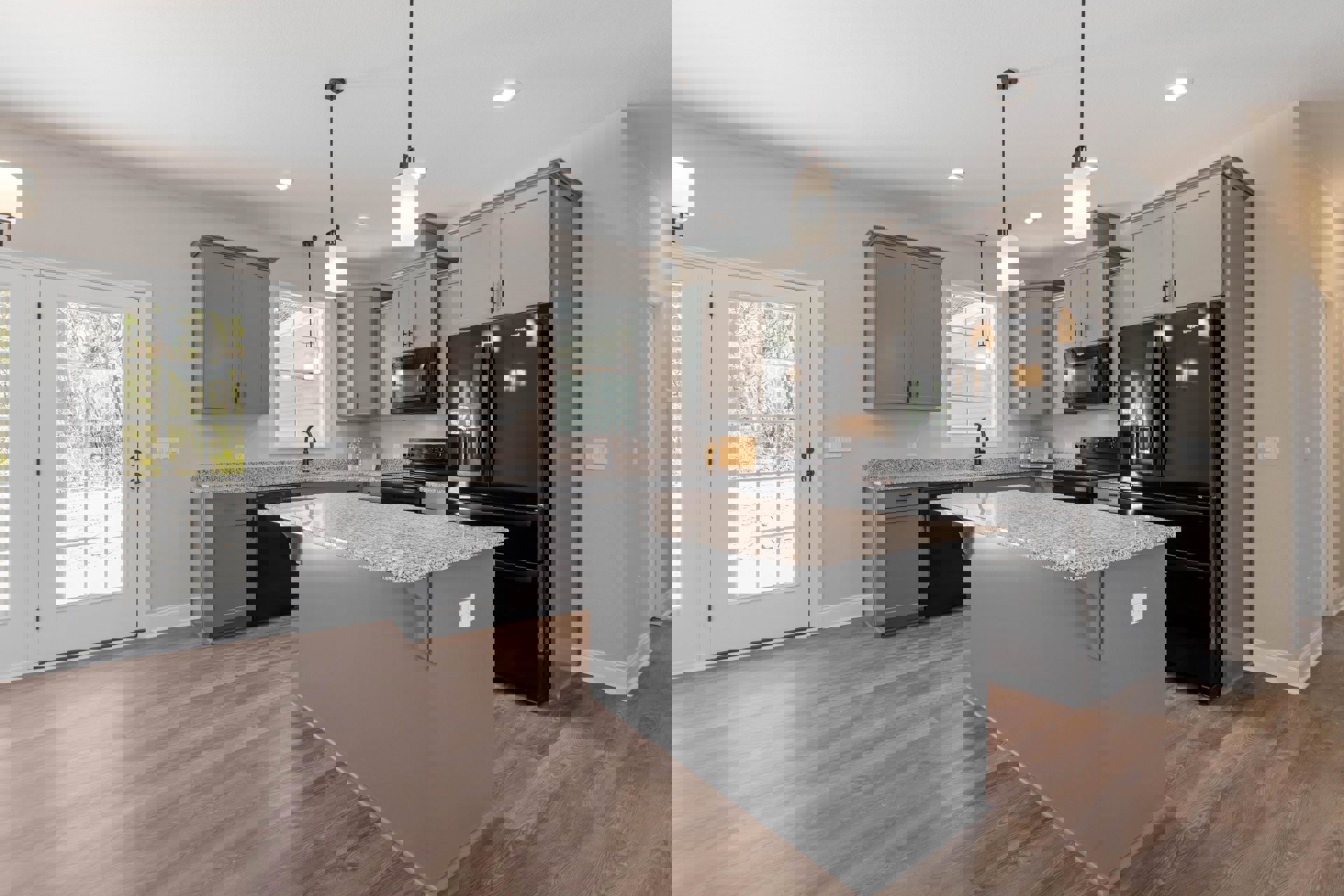 Kitchen with two black refrigerators, granite island countertop, white door opening to tree view, close-up of ceiling light fixture, pole-mounted light, mirrored refrigerator door