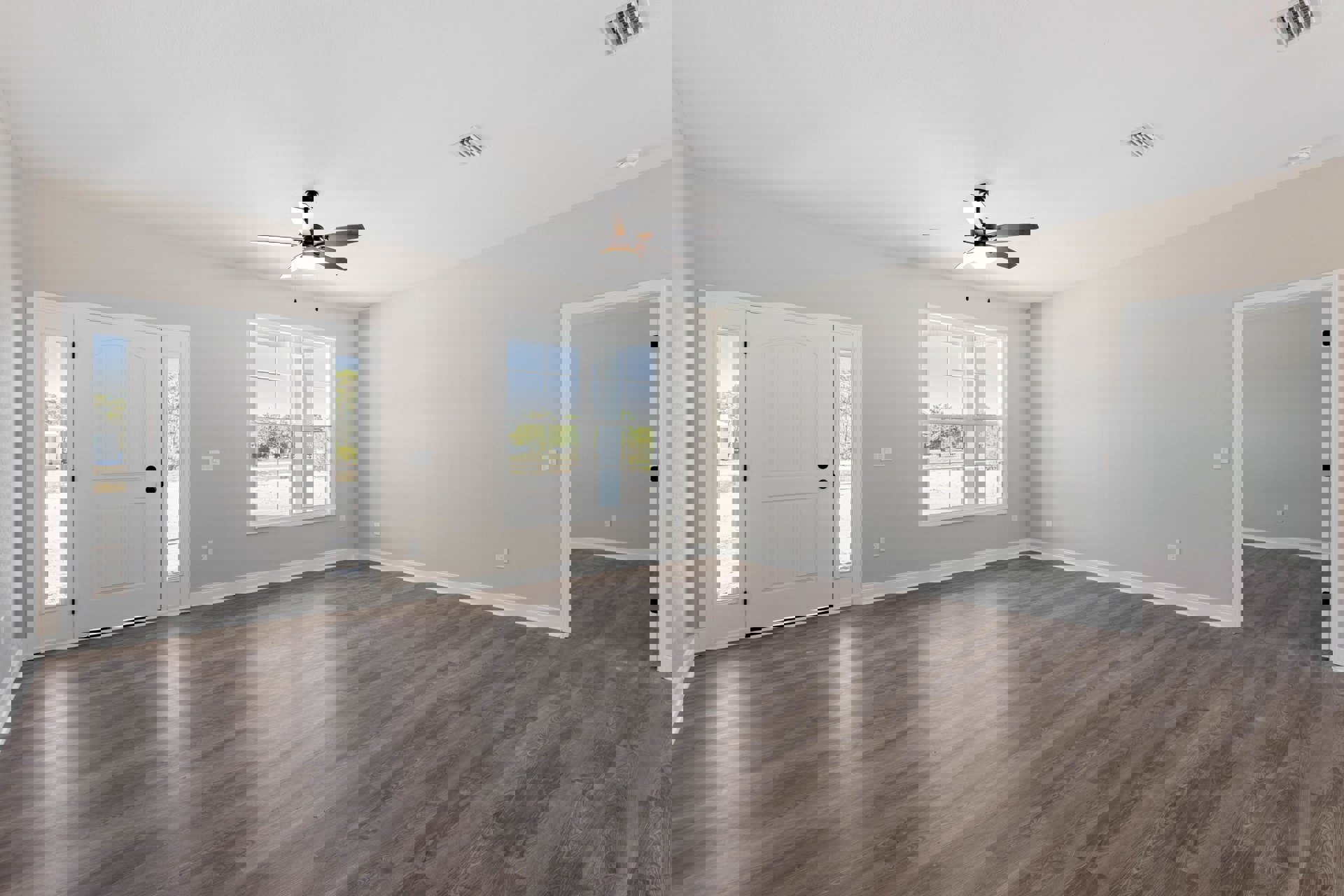 Wood flooring in a bright room featuring a ceiling fan with light, white door with glass panes, and window overlooking neighboring house
