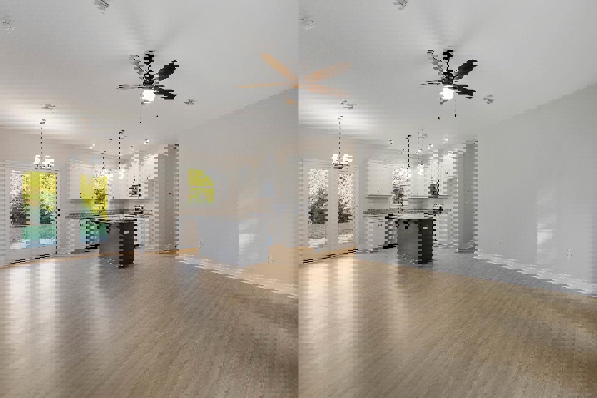 Open-concept kitchen and dining area with white walls, black kitchen island topped with marble, wood flooring, ceiling fan with light, and large window with overhead fixture