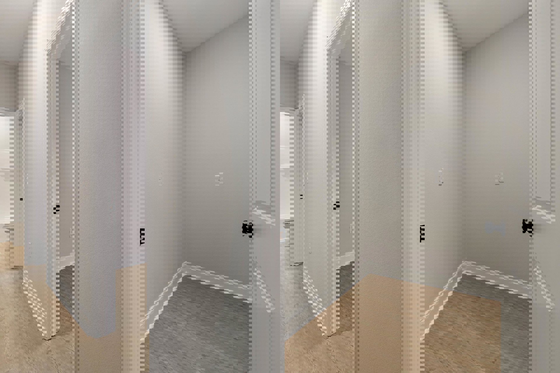 White hallway with open square-panel door, black door knob, wood flooring, white baseboards, and white walls