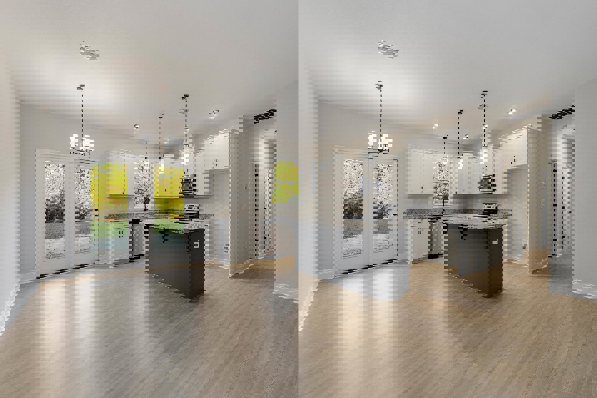 Open kitchen and dining area with wood flooring, granite countertops, white cabinetry, stainless steel microwave, double glass doors leading to backyard, forest visible through