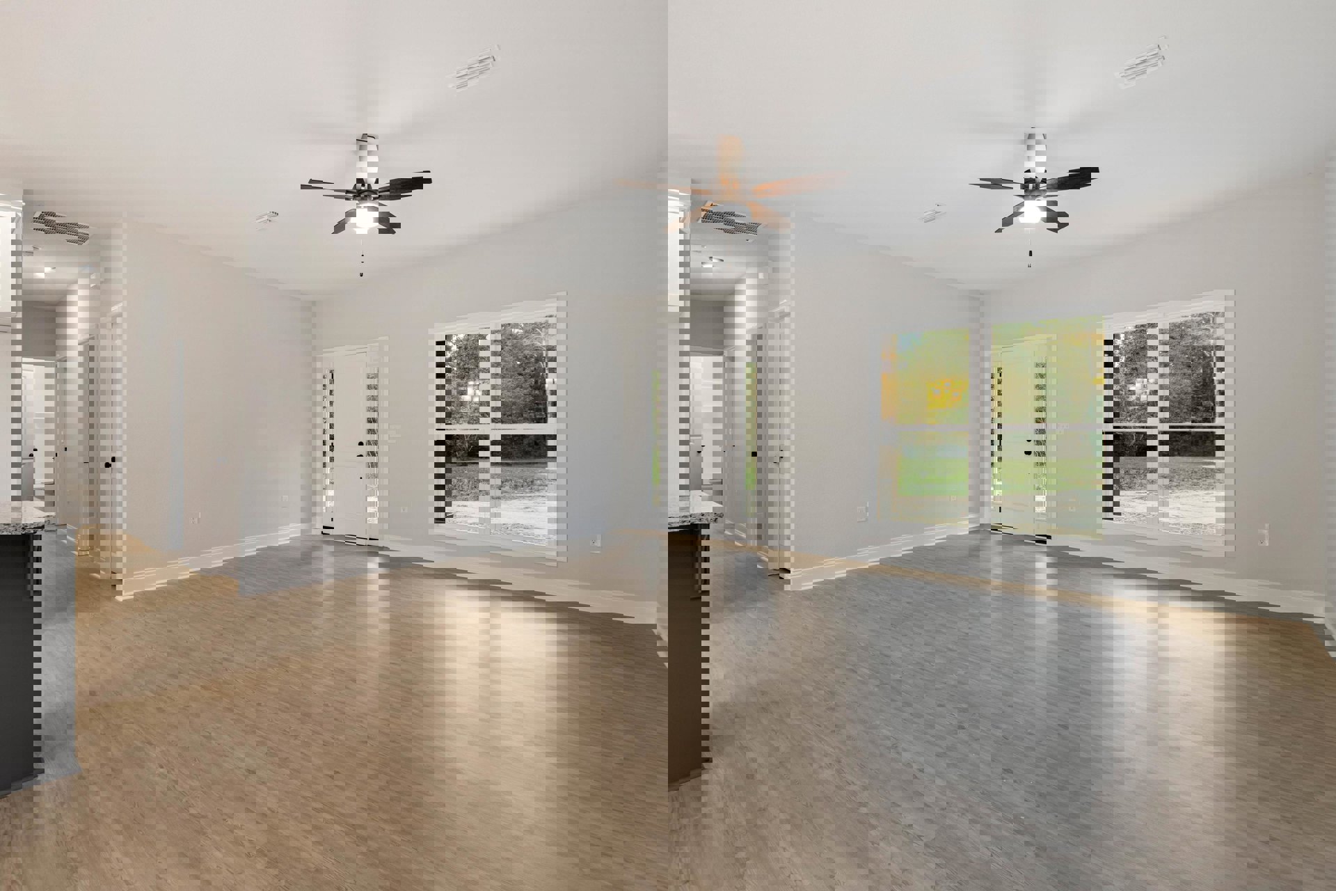 Living room with wood flooring, ceiling fan with light, double doors, white door with black handles, large window showing trees, black rectangular table with light brown top