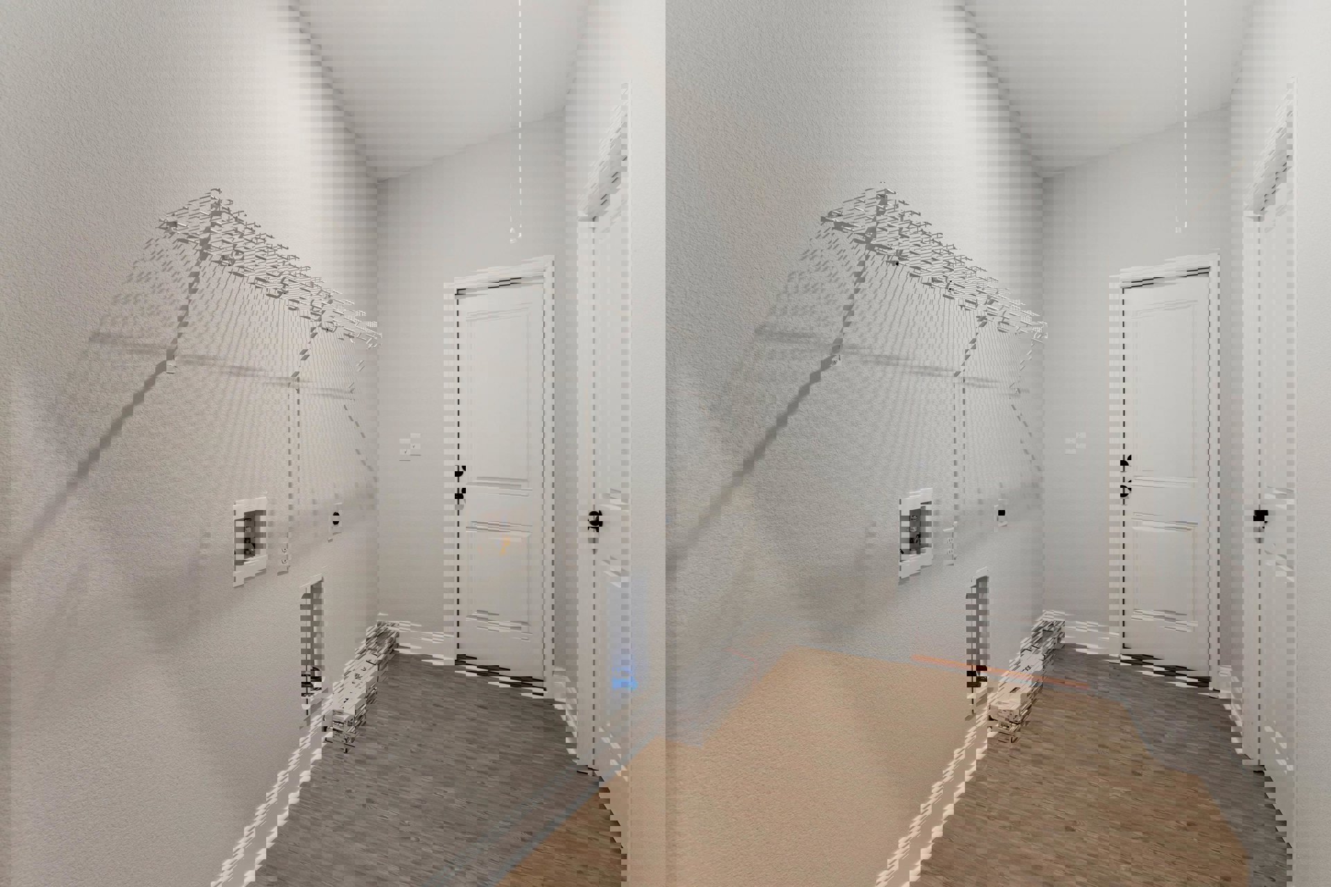 White-painted wall and door with black knobs, wood flooring scattered with moving boxes, exposed pipe in a white utility square, white rectangular object featuring a blue label