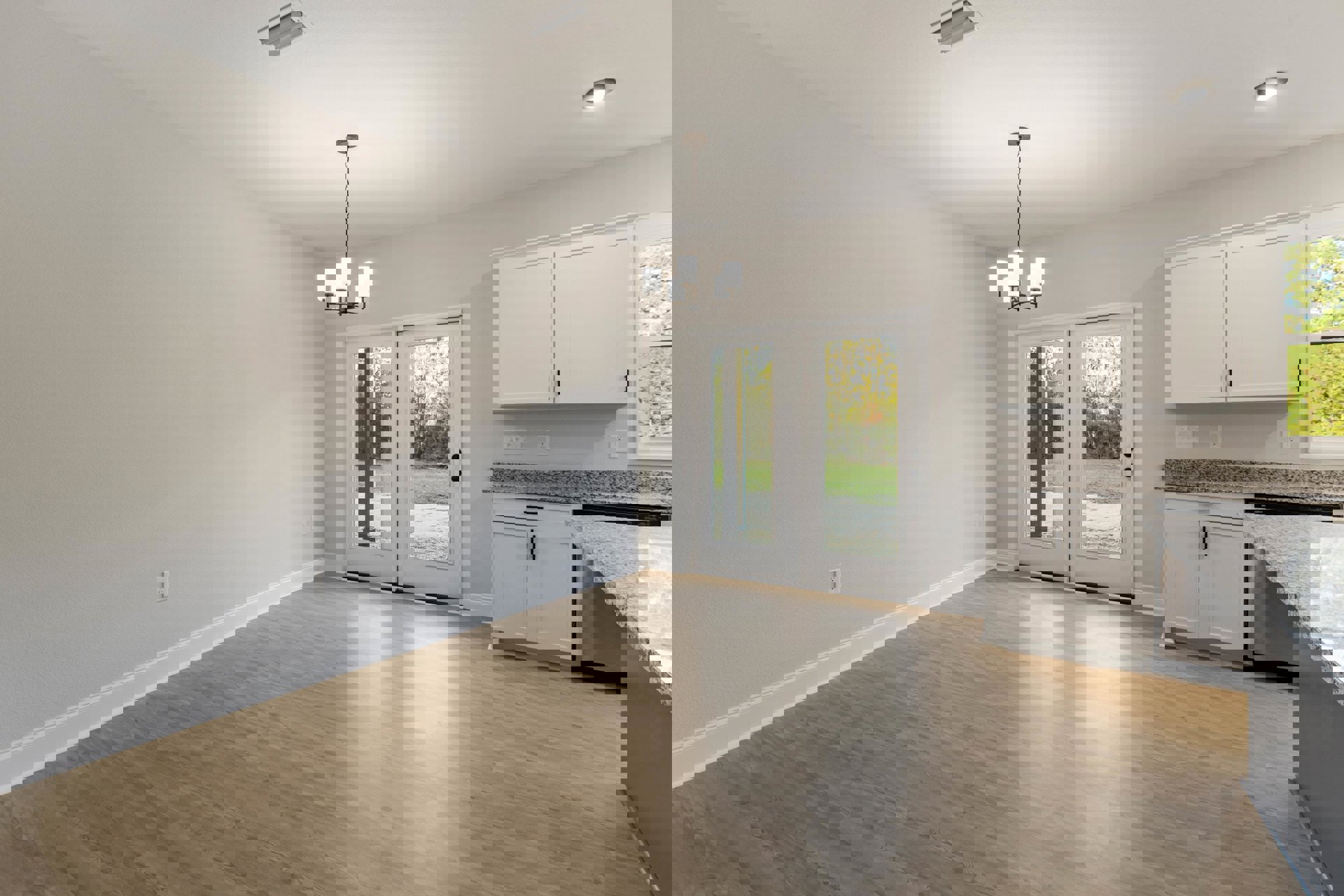 Wood floor room featuring double glass-paneled doors, white door with black hinges and handle, forest view through glass, white cabinetry, countertops, and kitchen sink.