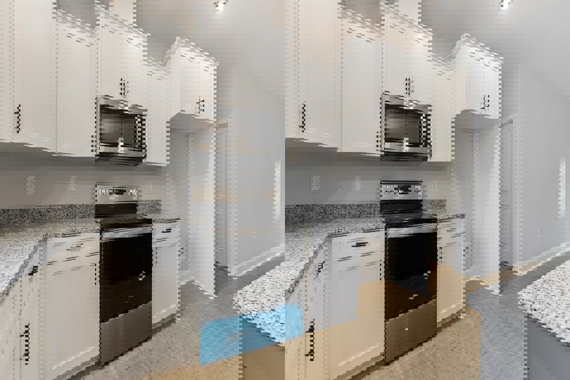 White kitchen cabinets with black handles, black and silver stove, built-in microwave, white door, light countertop.